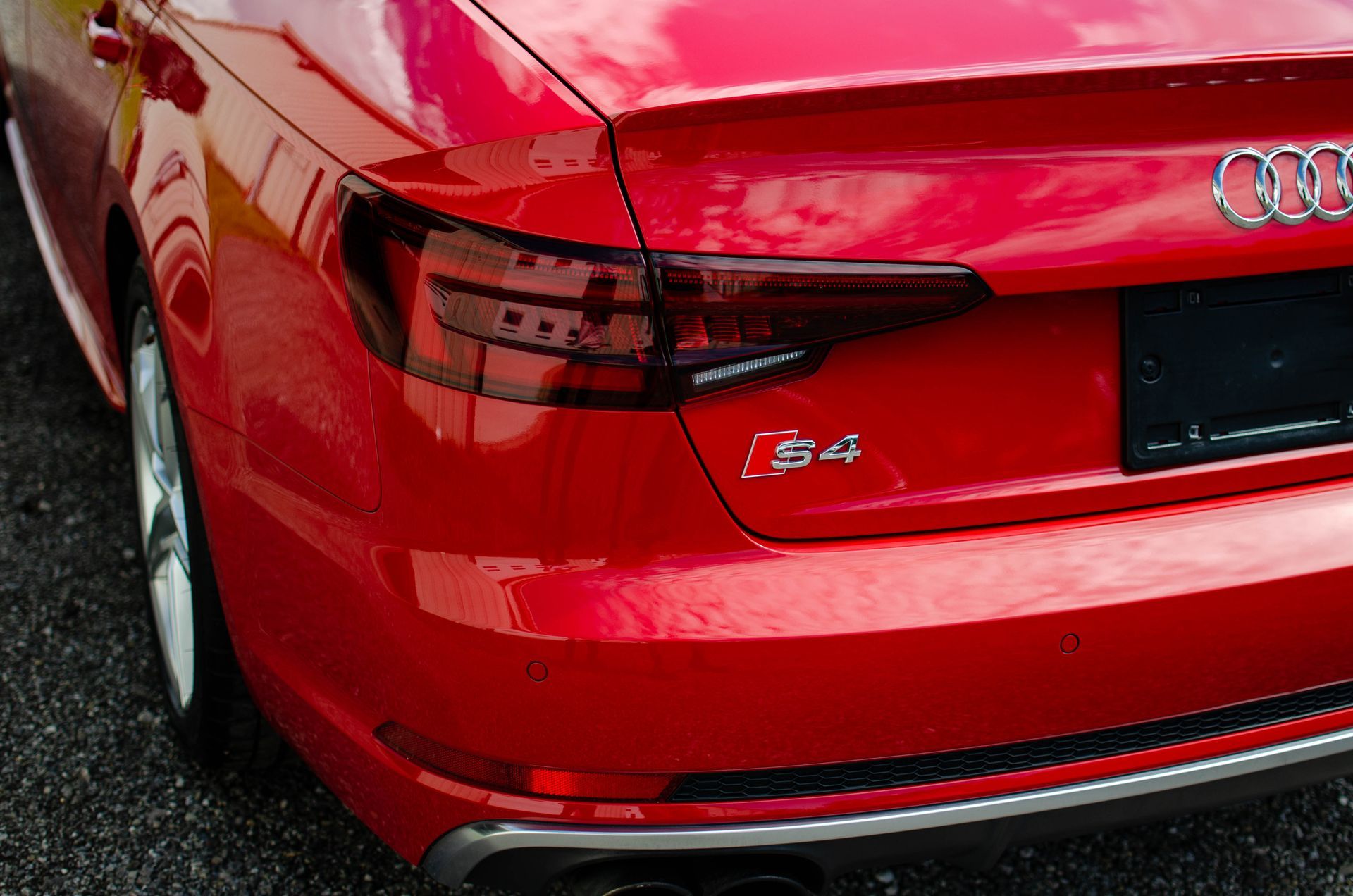 Red Audi S4 rear quarter in bright red, showing taillight and trunk badge on a wet road
