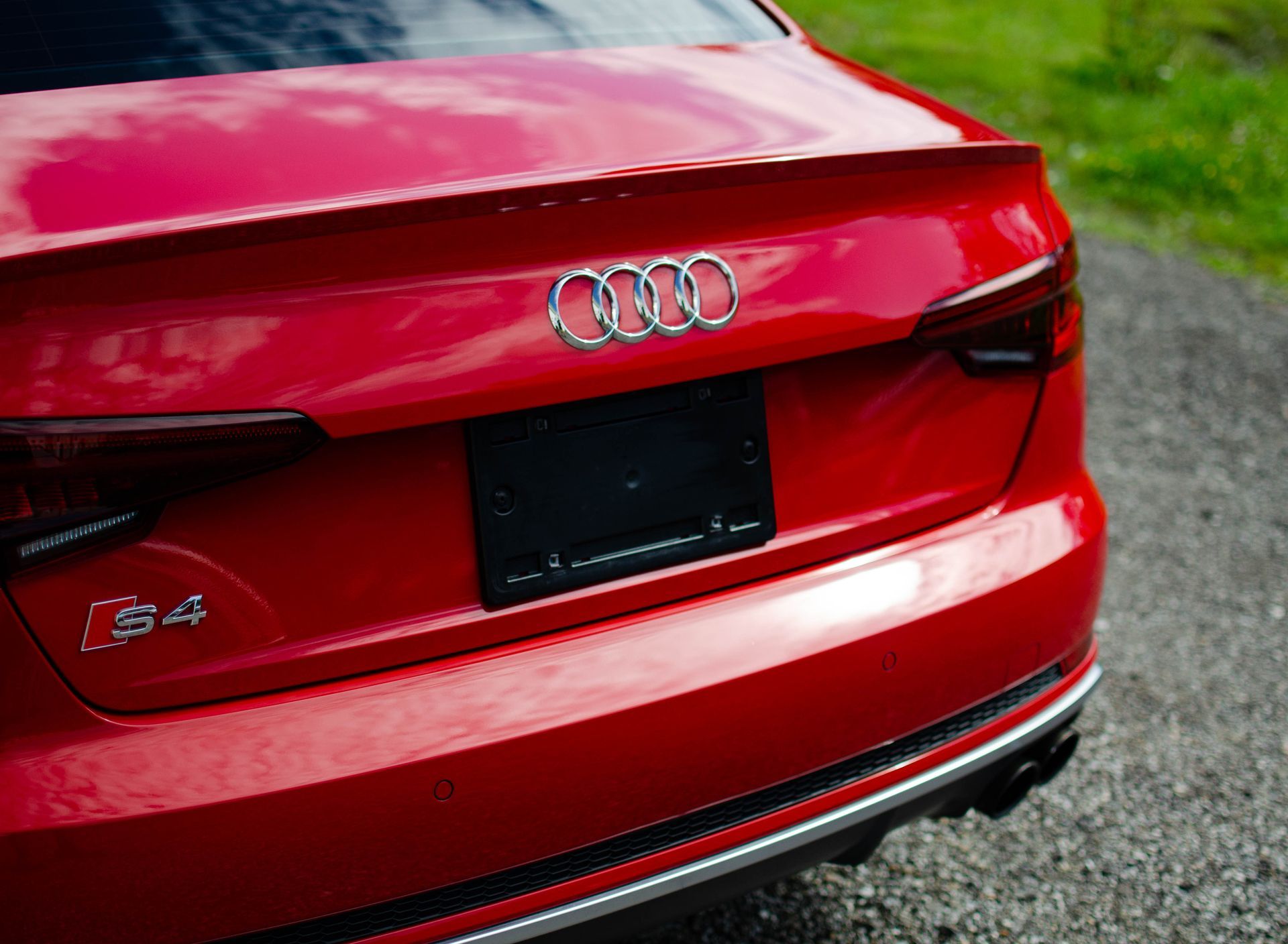 Rear view of a red Audi S4 with a blank license plate area on a road