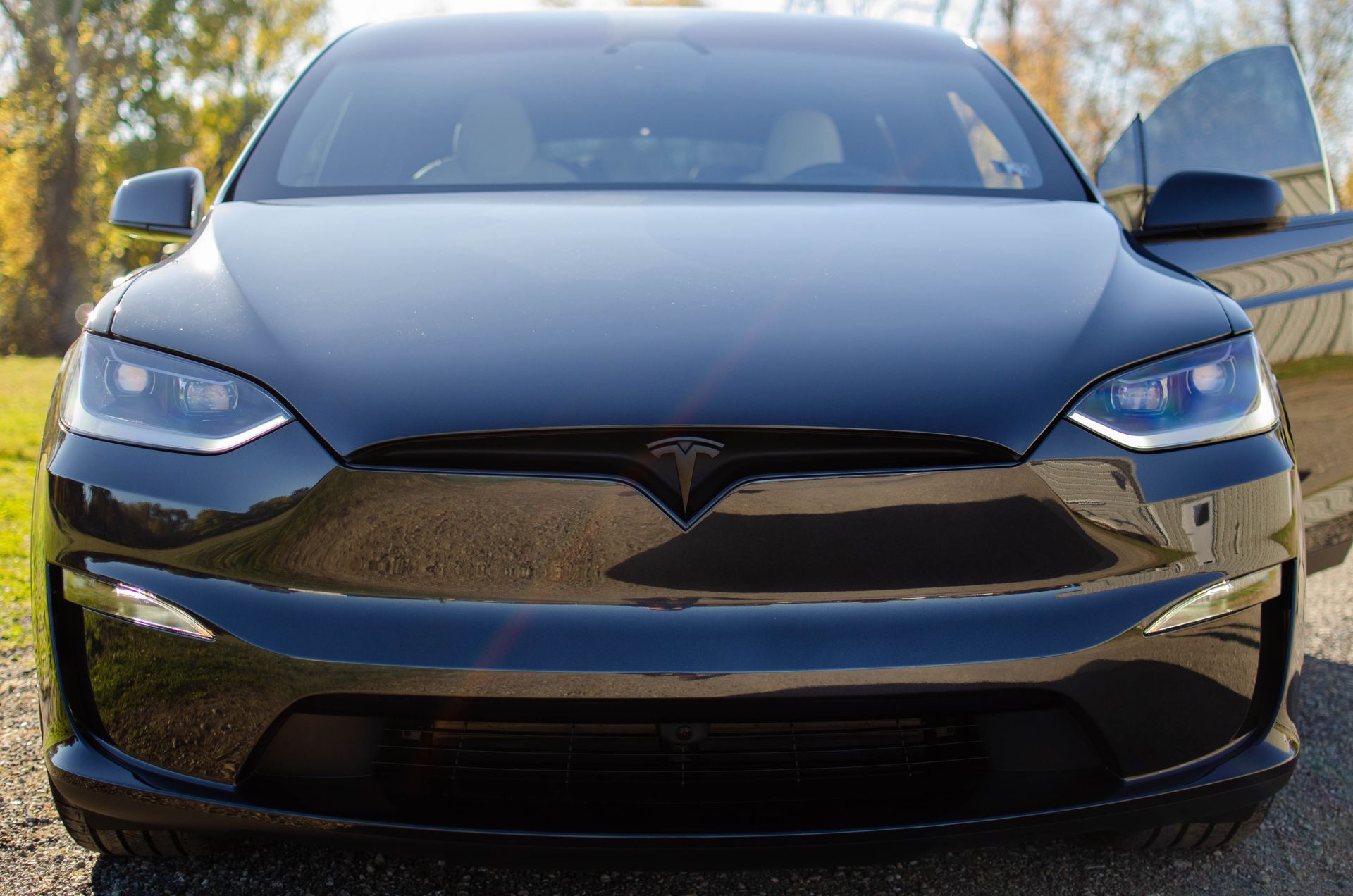 Front view of a black Tesla sedan parked outdoors in sunlight
