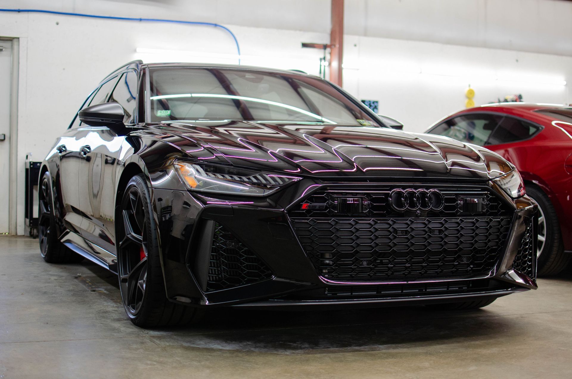 Black sedan parked indoors in a garage, front view with glossy finish and tinted windows