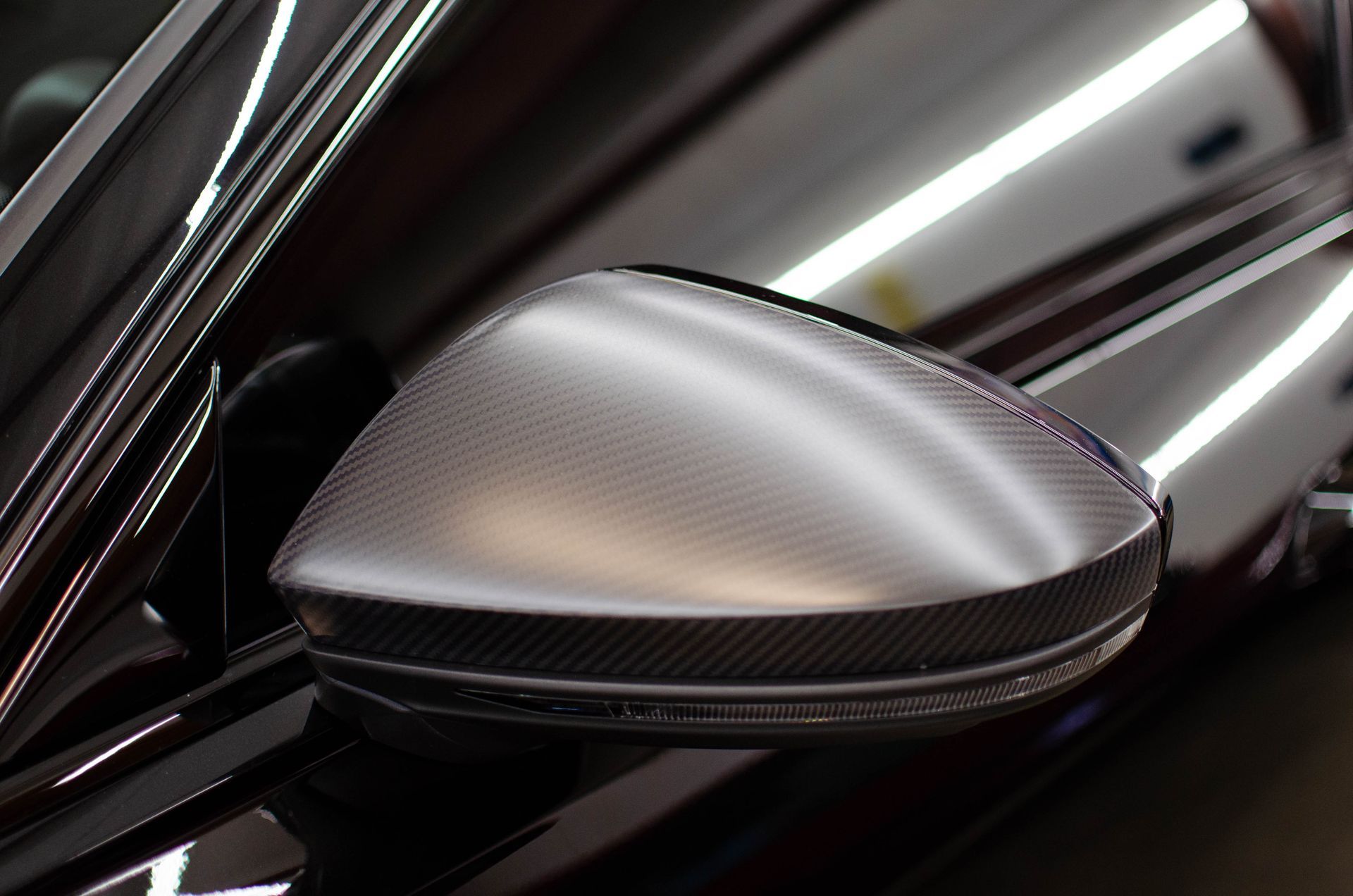 Close-up of a silver car side mirror on a black vehicle body