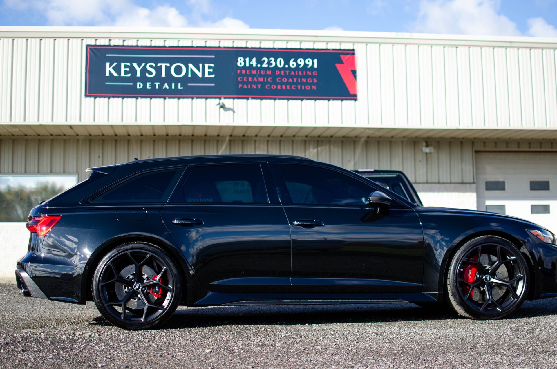 Black SUV parked in front of a Keystone sign on a building, side view