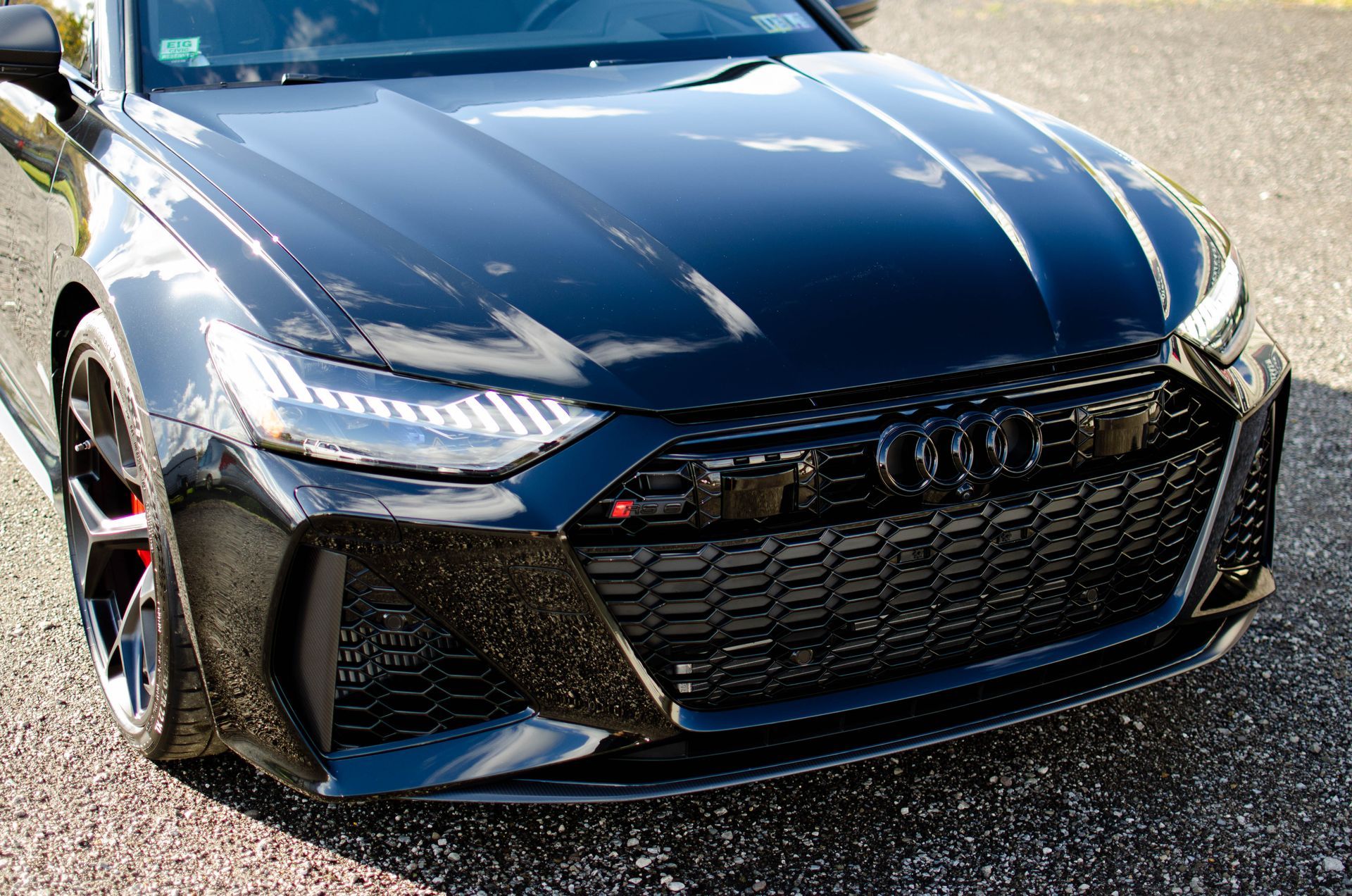 Black sports sedan parked outdoors, front view with glossy finish and LED headlights