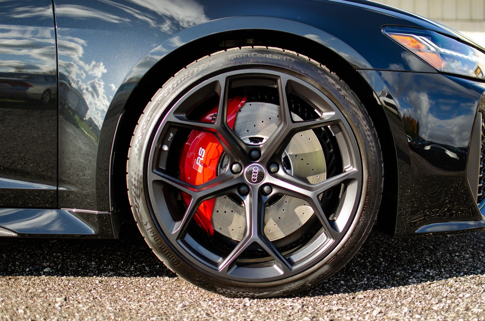 Close-up of a black sports car wheel with gray rim and red brake caliper