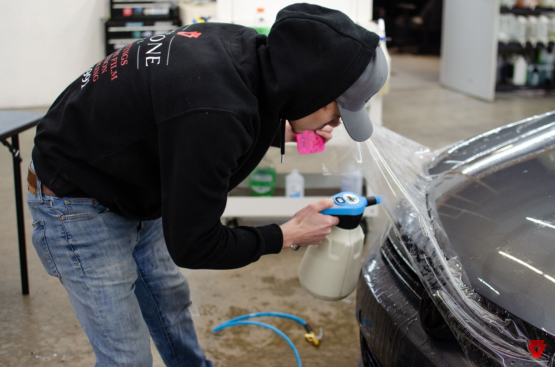 Wrapping a car with plastic wrap in a garage .