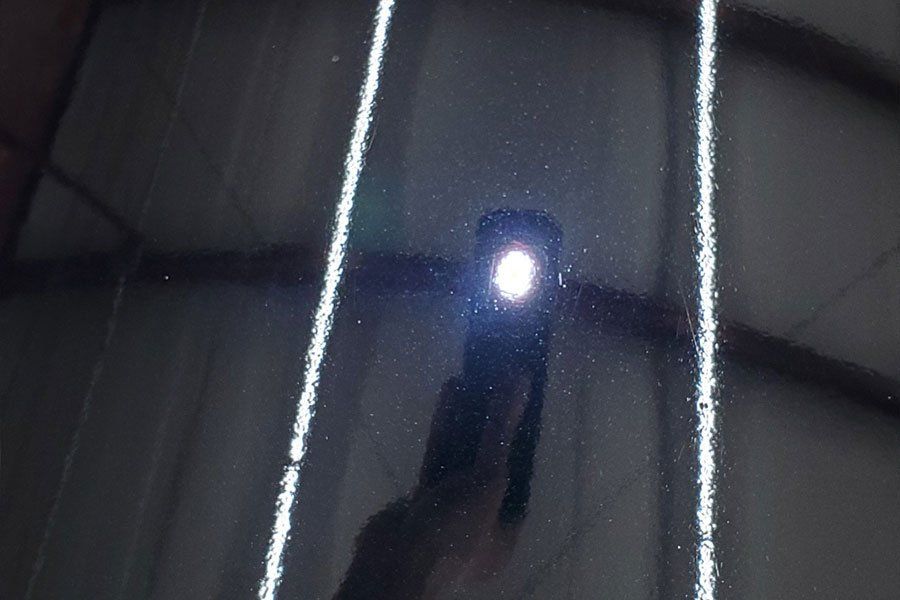 a person is taking a picture of a black car with a flashlight .