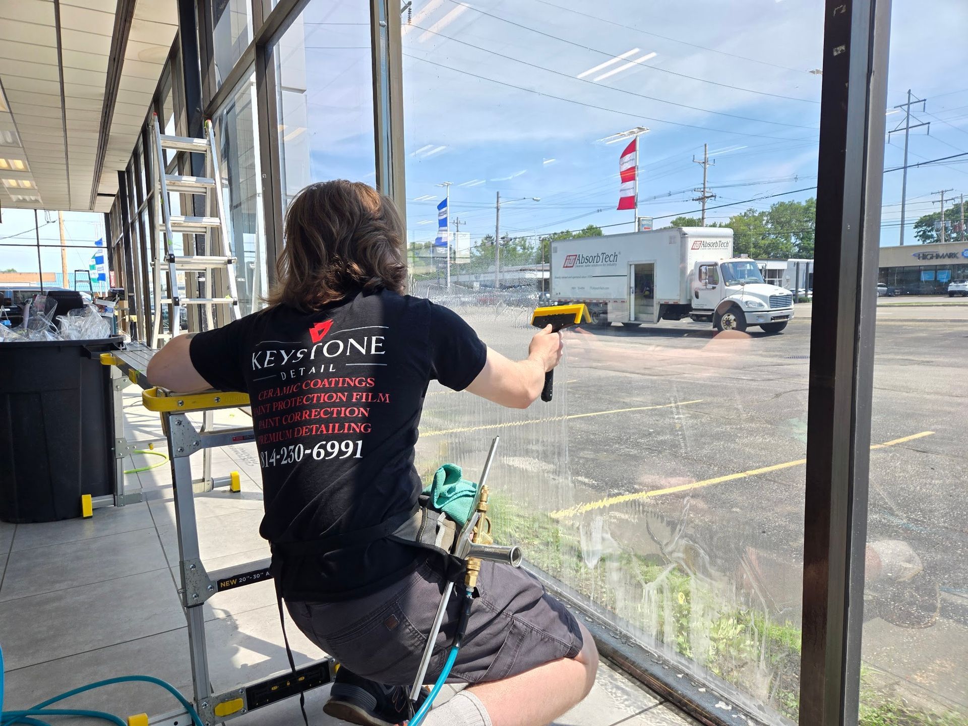 Keystone Detail technician squeegeeing commercial window film onto dealership glass in Erie, PA