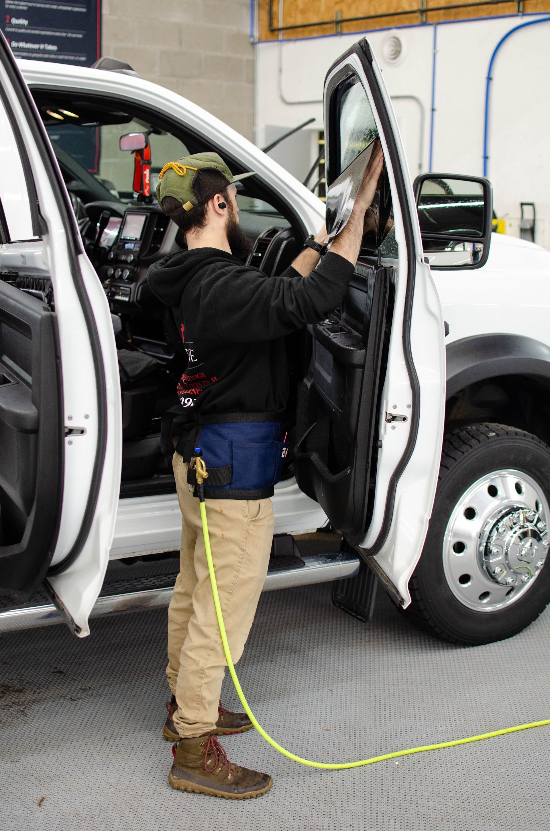 Keystone Detail technician installing window tint inside a RAM 2500 cab, Waterford, PA