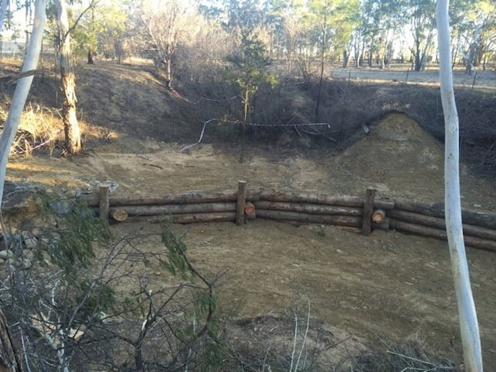 A Wooden Fence Surrounds a Dirt Field With Trees in the Background — Total Vegetation Management in Braemar, NSW