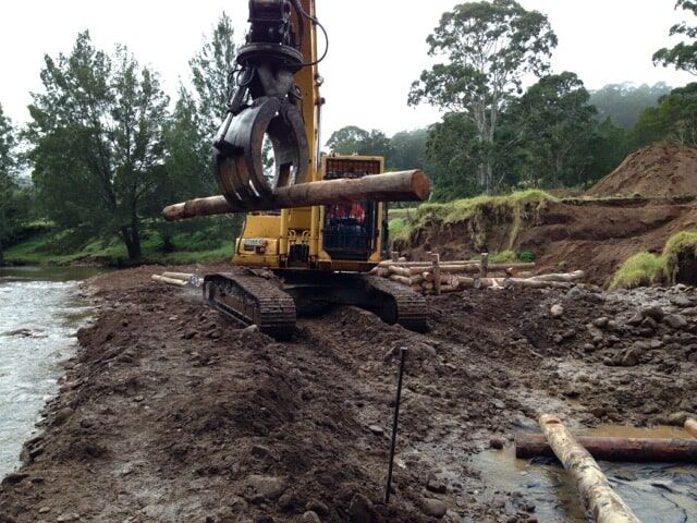 A Bulldozer is Lifting a tree log from mud— Total Vegetation Management in Braemar, NSW