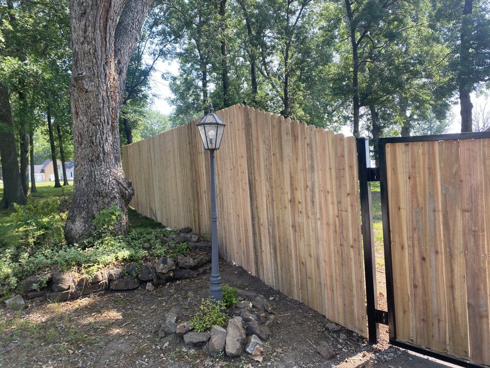 Wooden fence beside a lamppost and trees in a wooded yard