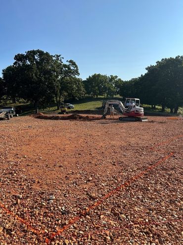 Construction site with excavators on a red dirt lot under a clear blue sky