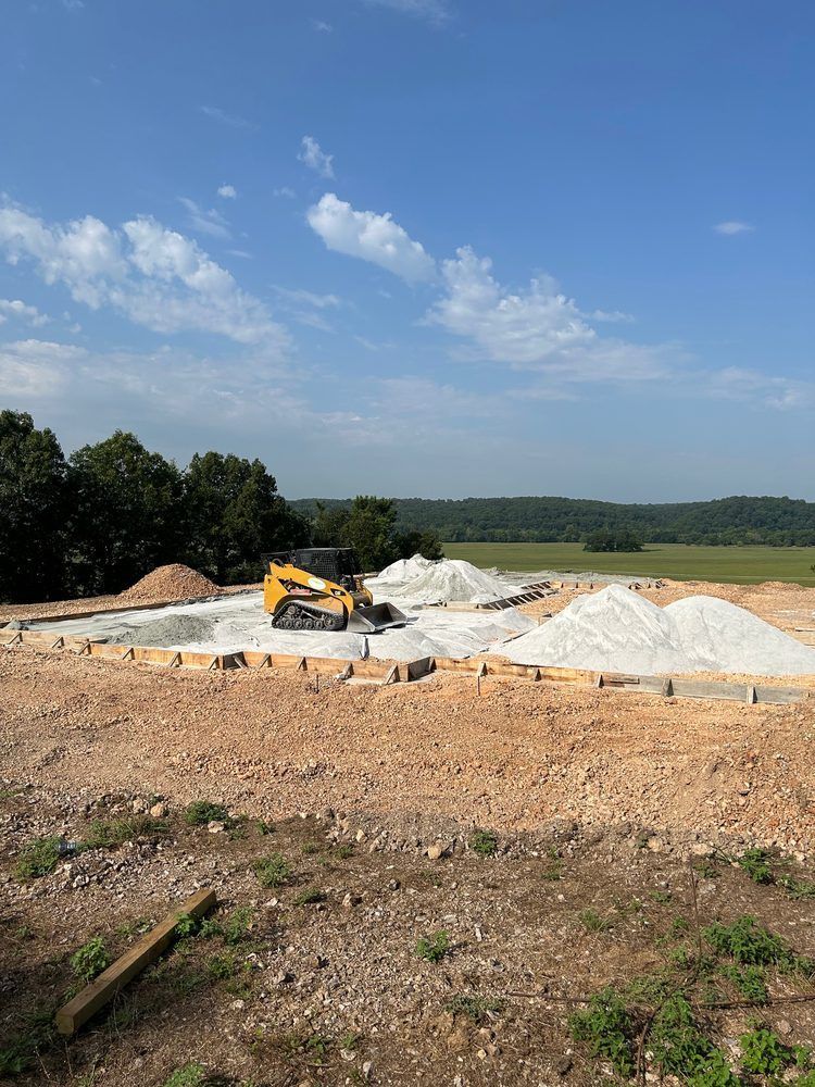 Construction site with a yellow excavator on gravel piles under a blue sky