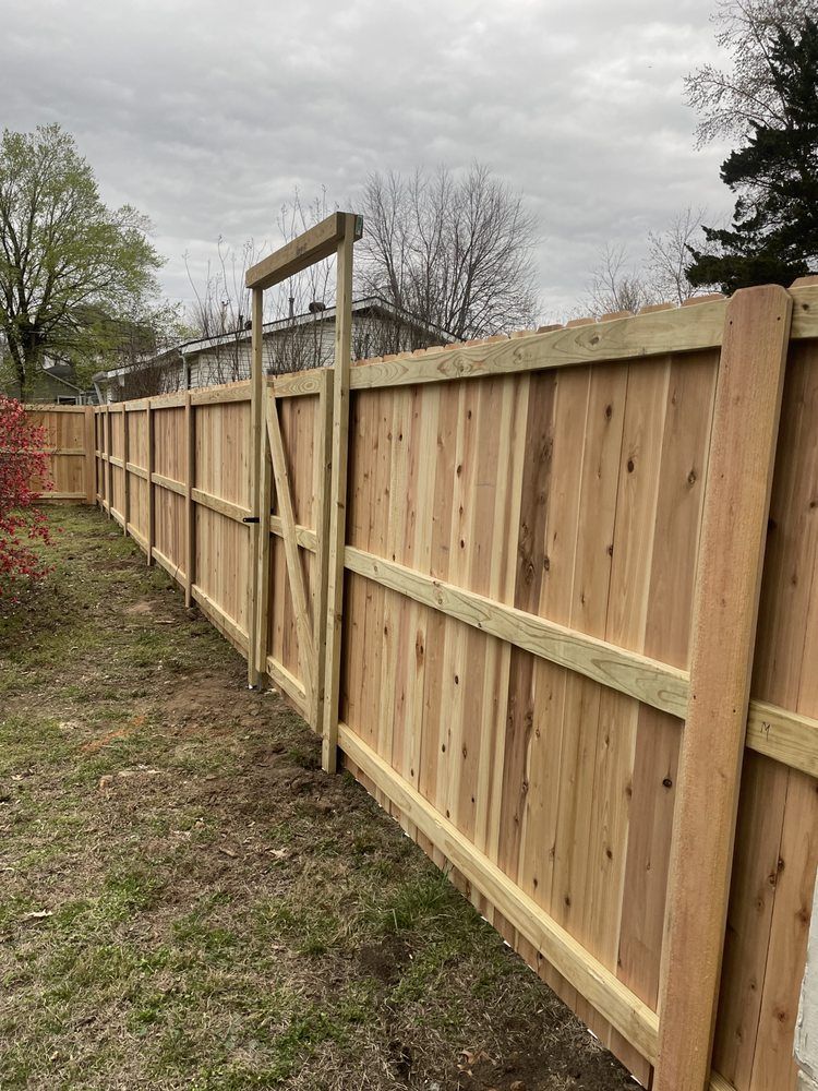 New wooden privacy fence with gate along a grassy yard under a cloudy sky