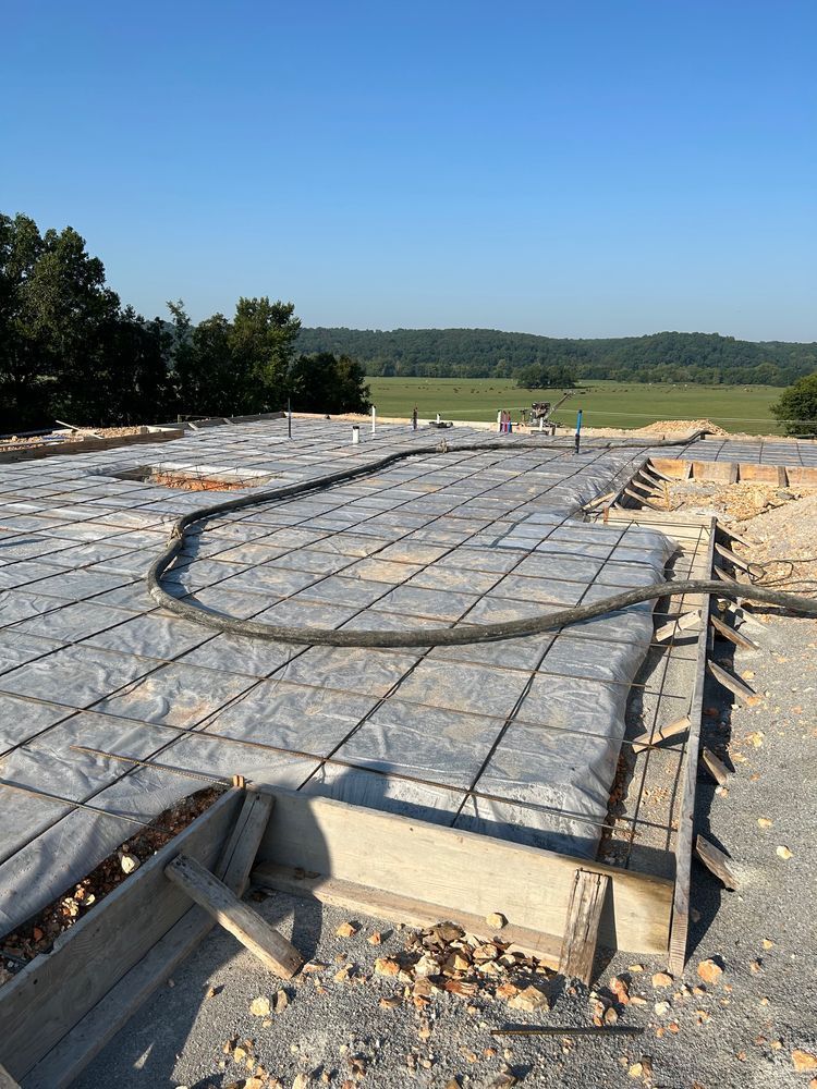 Concrete foundation slab with rebar mesh and wooden forms at a construction site under a clear sky