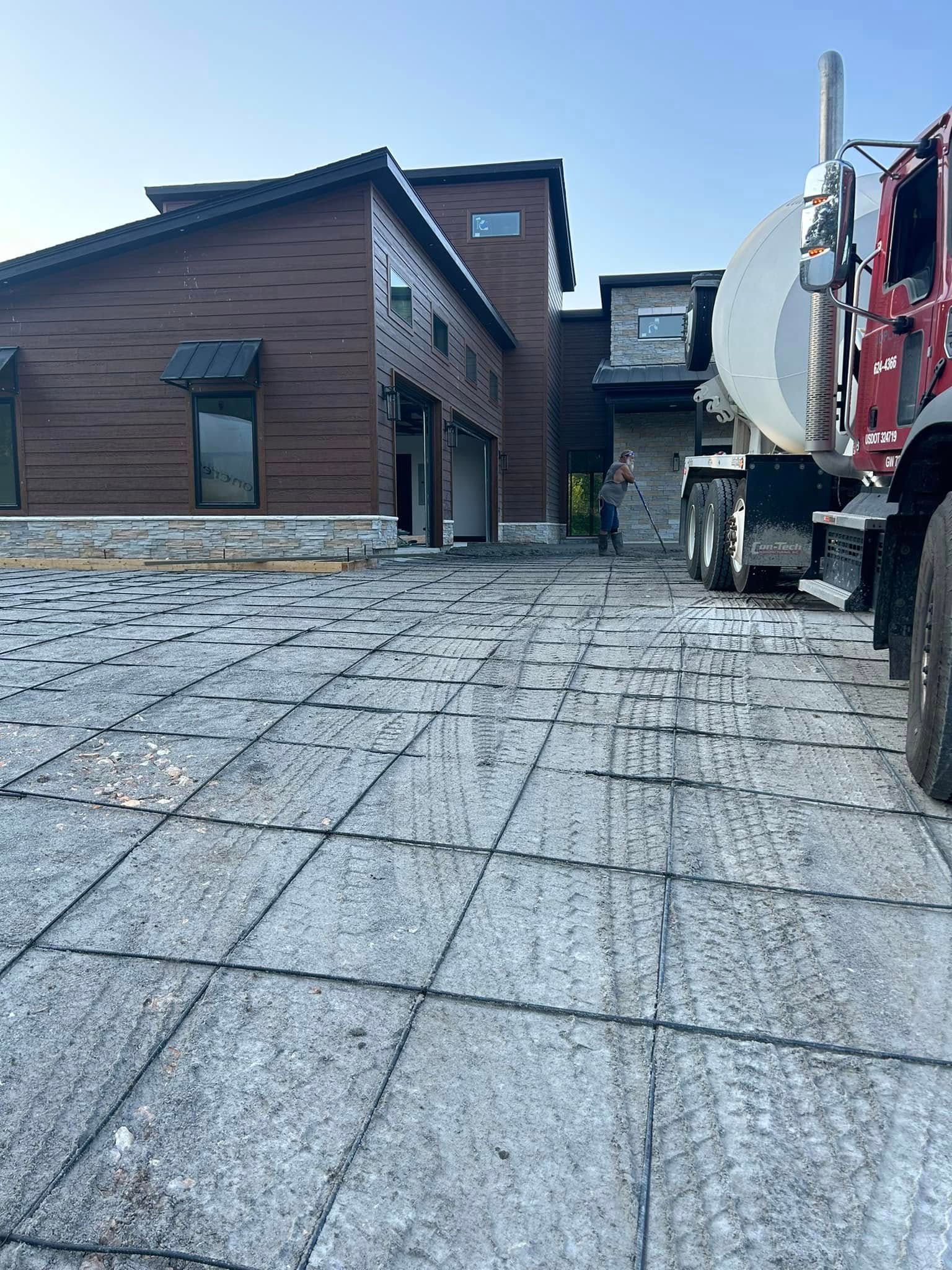 Brick house with paved driveway and a red truck on the right under a clear sky