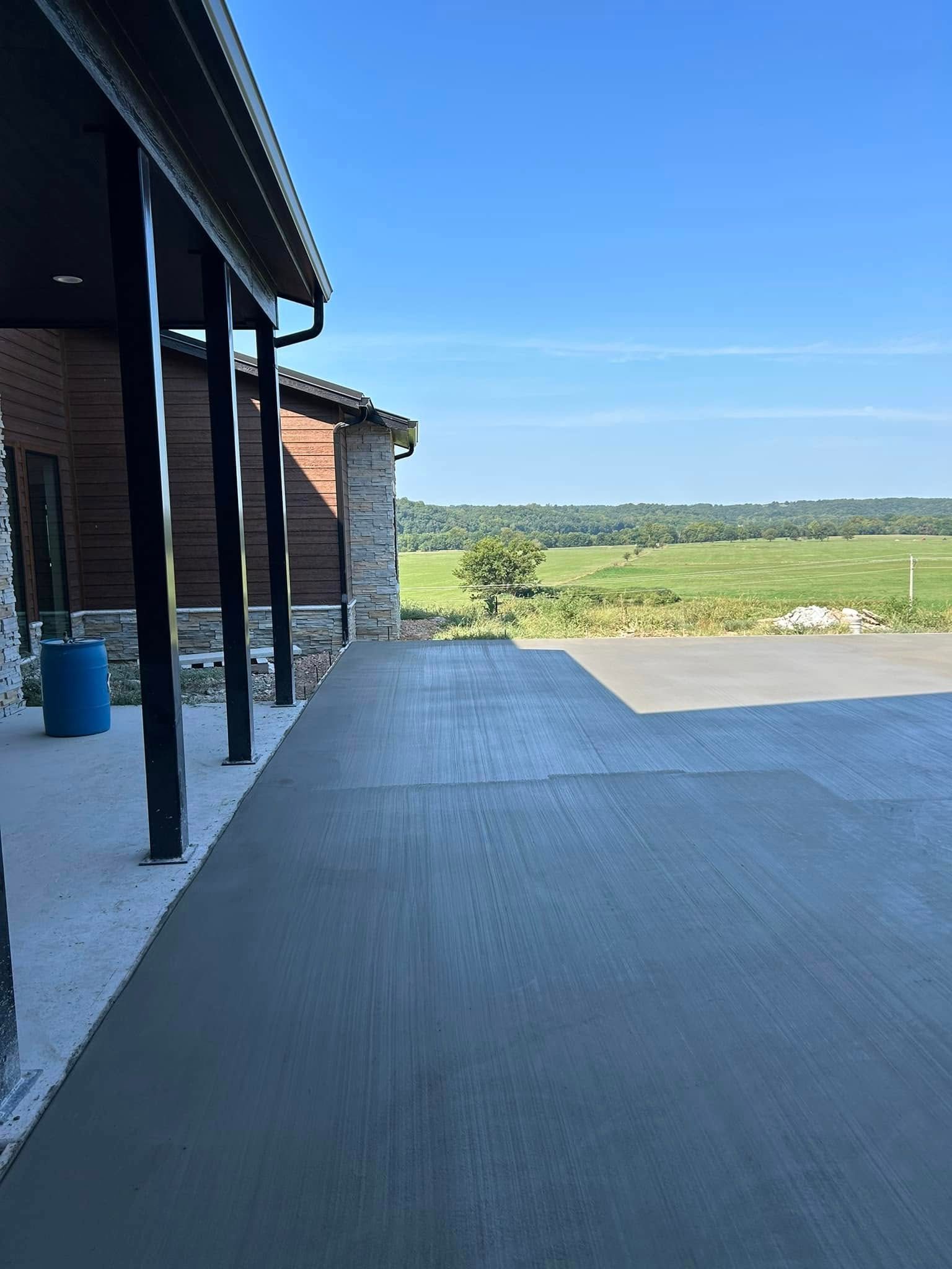 Covered patio overlooking green fields under a clear blue sky.