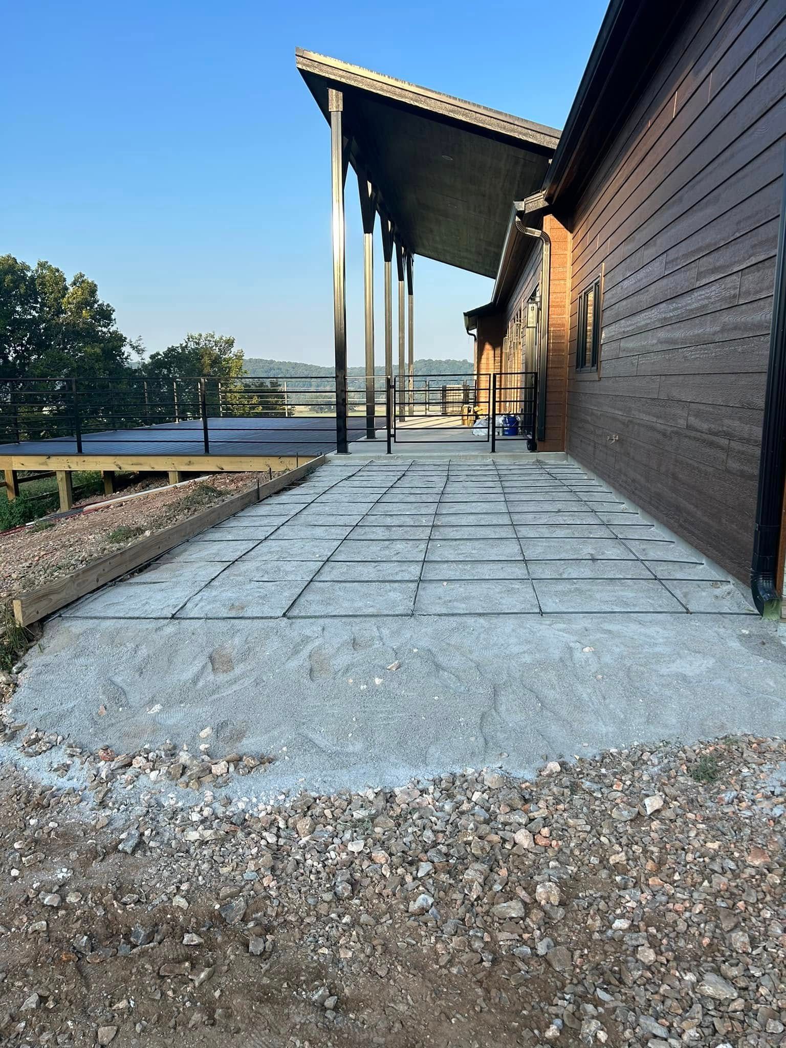 Stone walkway beside a dark wooden building with a slanted roof, overlooking water at sunset