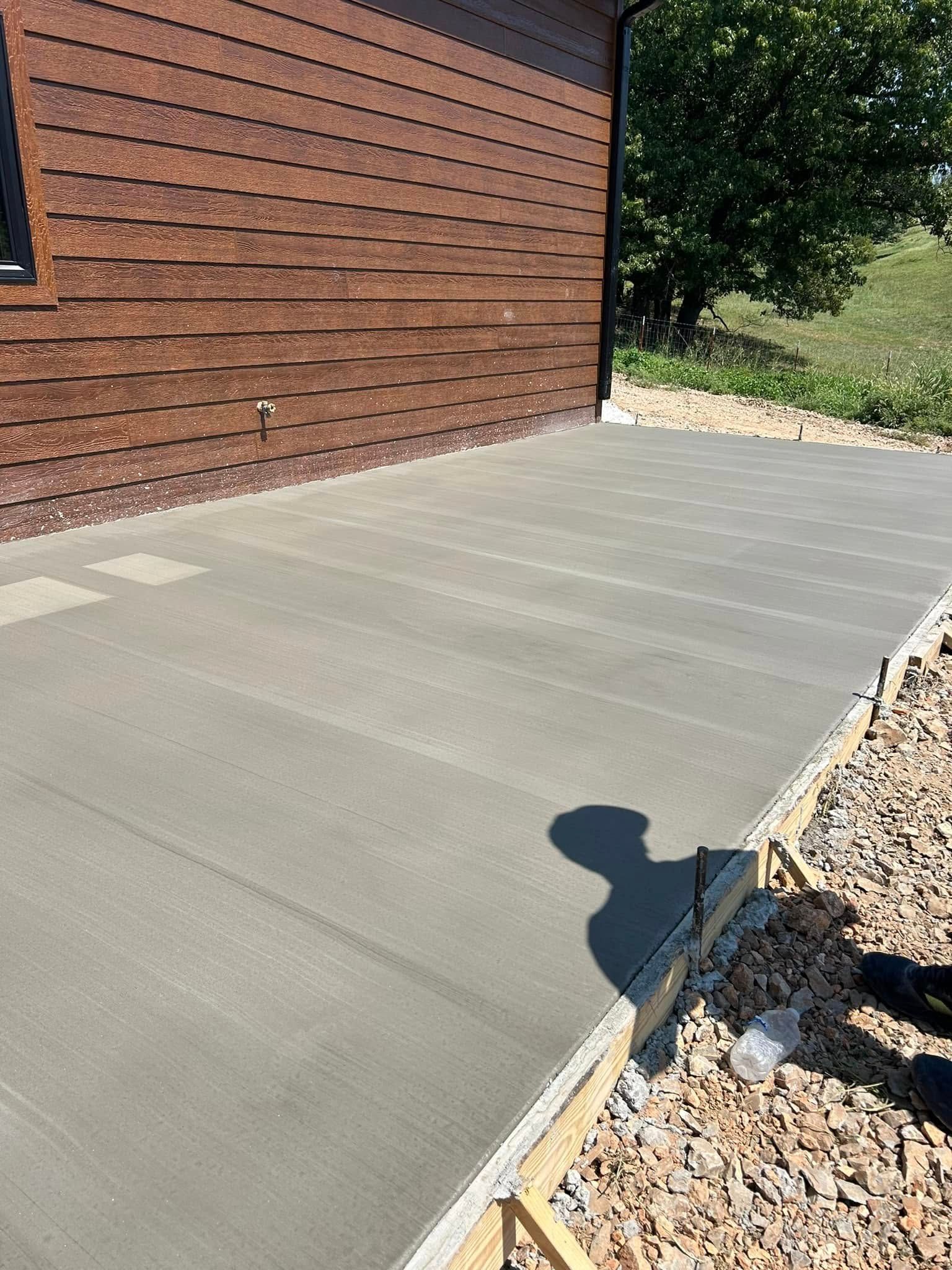 Concrete patio beside a brick wall and gravel landscaping in bright sunlight.