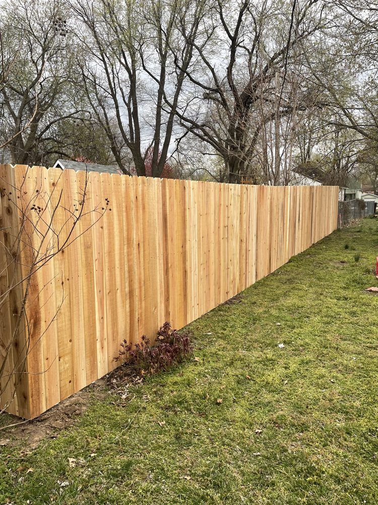 New wooden privacy fence along a grassy yard with bare trees in the background