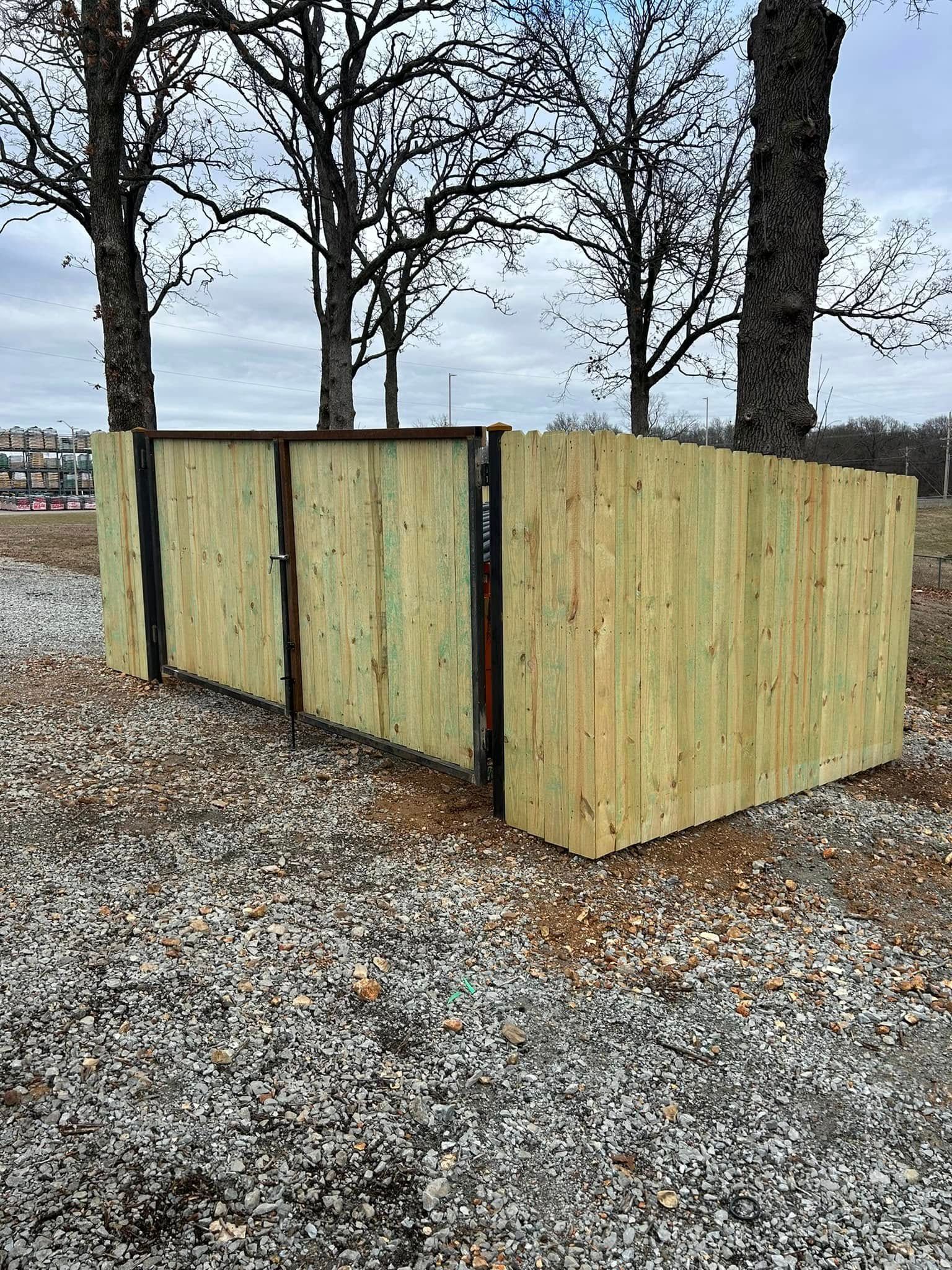 Wooden compost bin or enclosure in a leaf-covered park with bare trees in the background