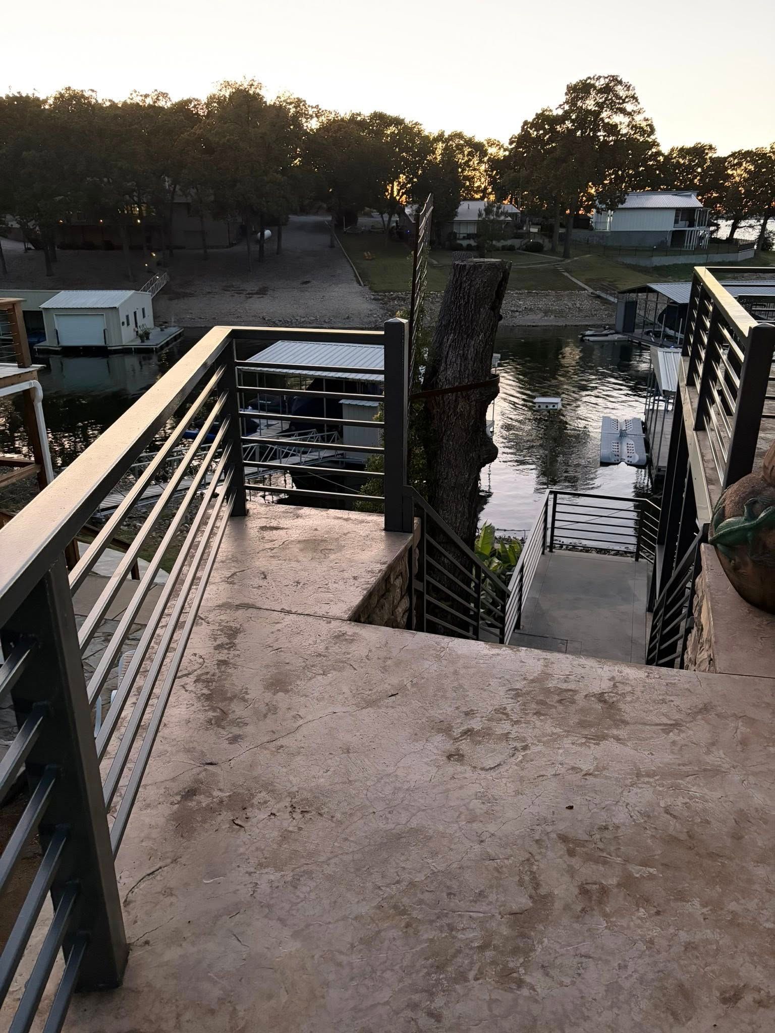 Concrete dock walkway with metal railings leading to a calm waterfront at sunset