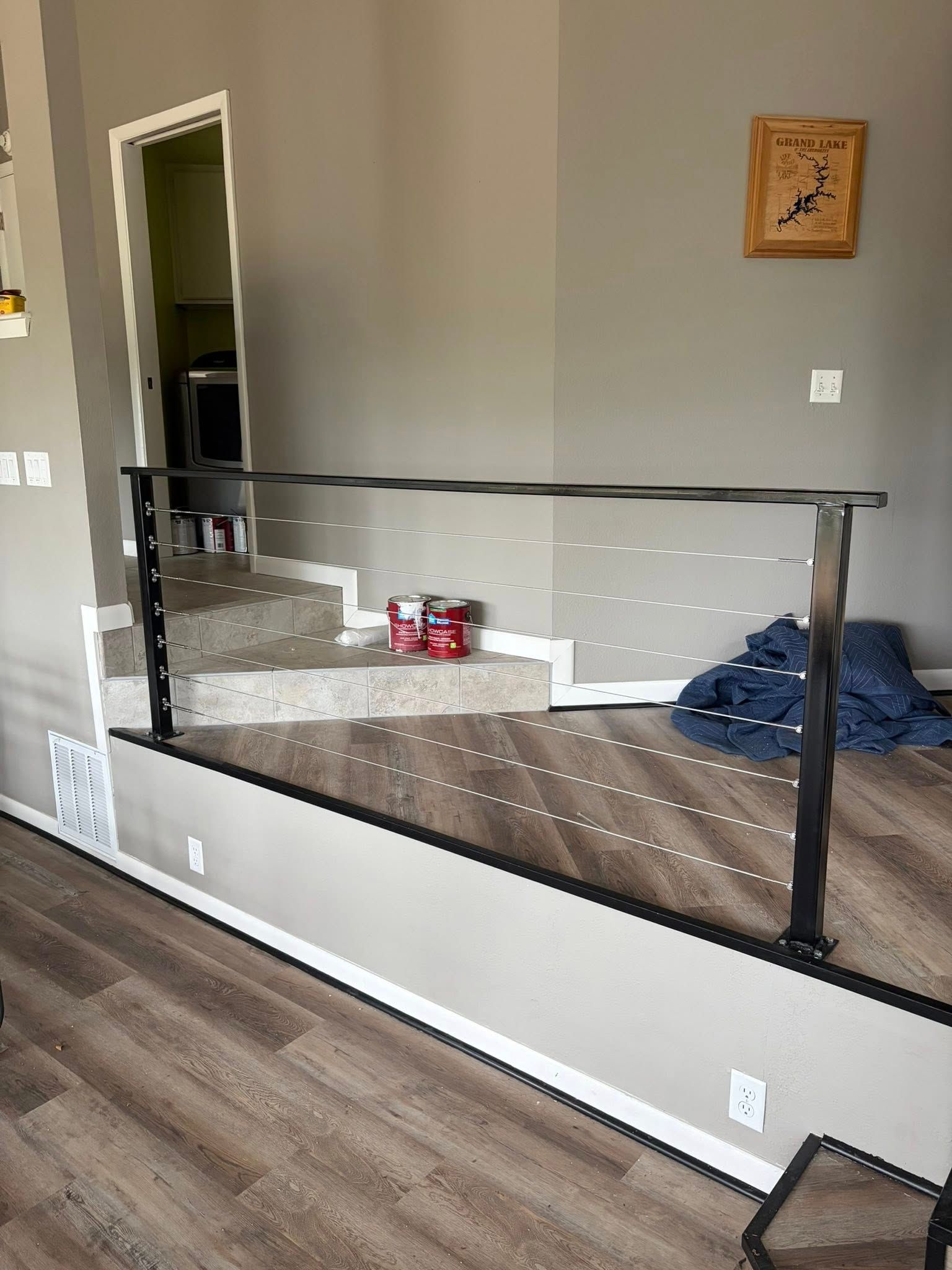 Indoor home scene with a black safety gate across a stair opening and toys on the floor