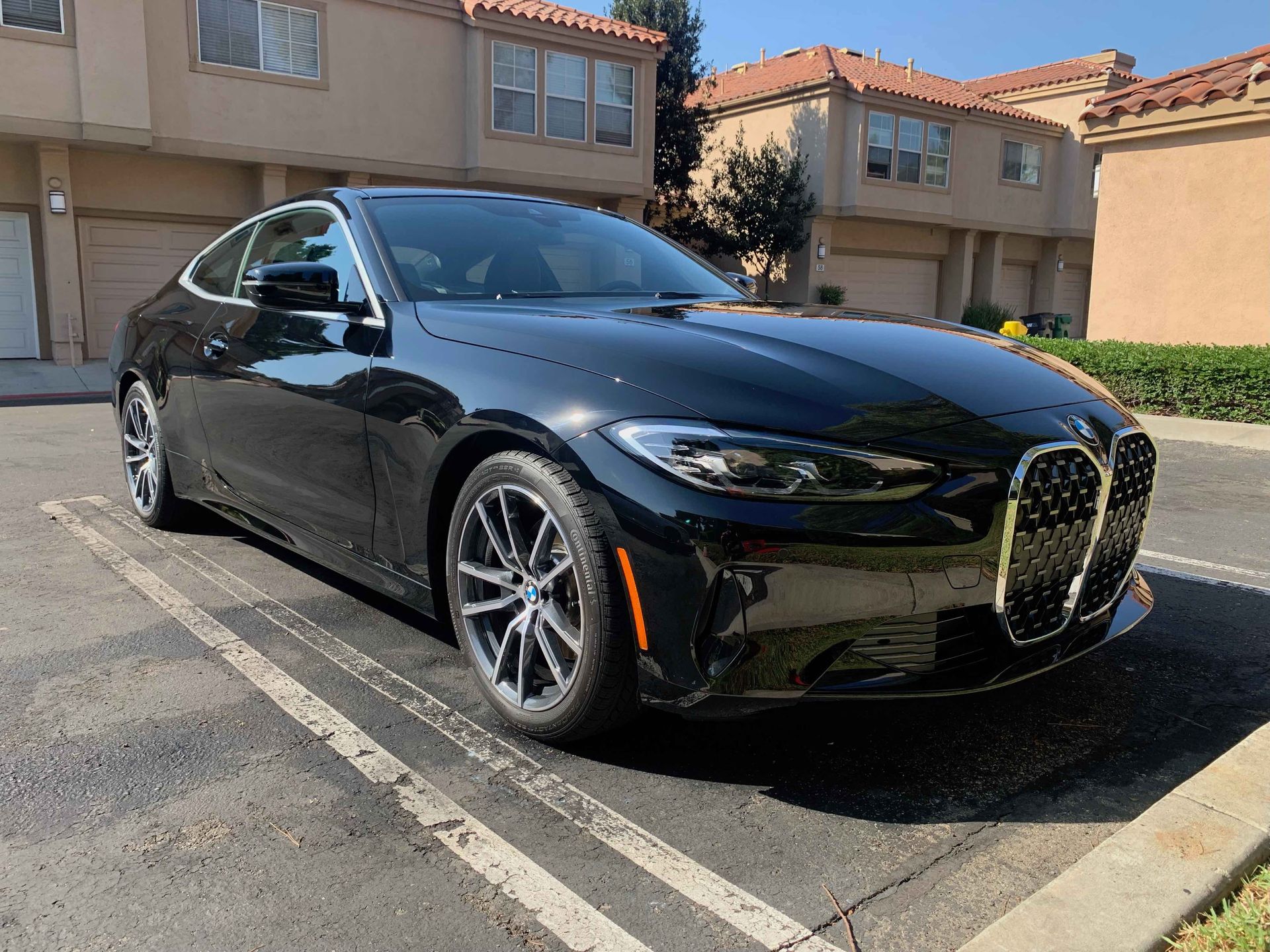 A black BMW 4 Series coupe parked in a paved residential driveway.