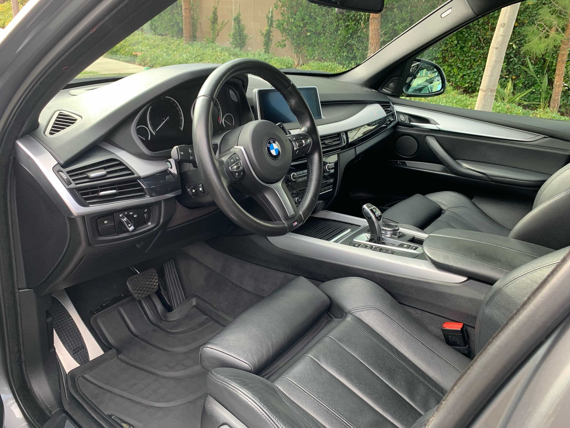The interior of a black BMW with leather bucket seats, a multi-function steering wheel, and a modern dashboard.