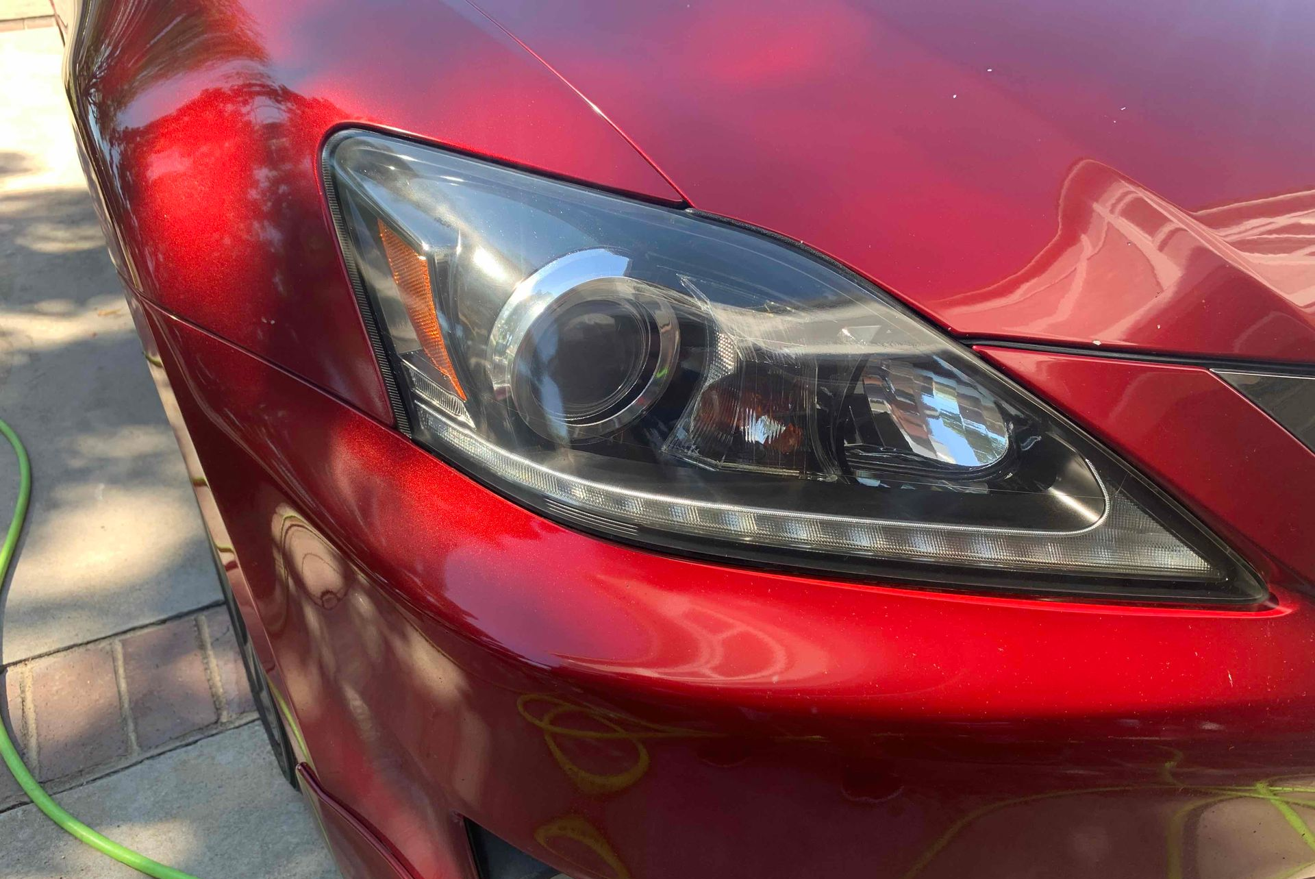 Close-up of a modern, sleek projector-style headlight assembly on a white and dark grey vehicle exterior.