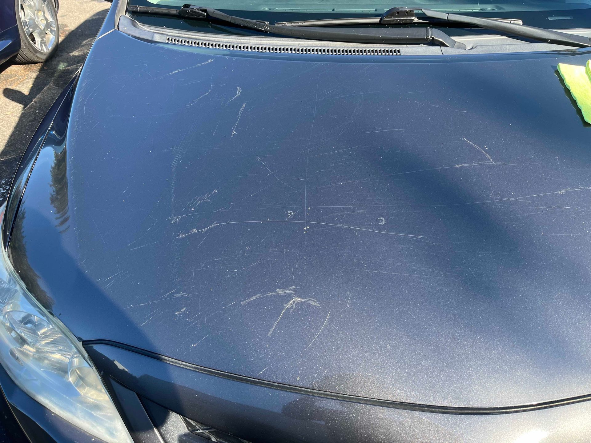 A dark grey car hood marked with several thin, light-colored scratches.