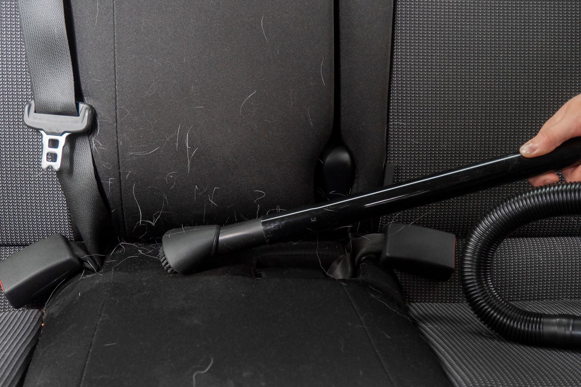 Interior of a red and black sports car showing tan leather seats and dashboard, a black steering wheel, and the windshield.