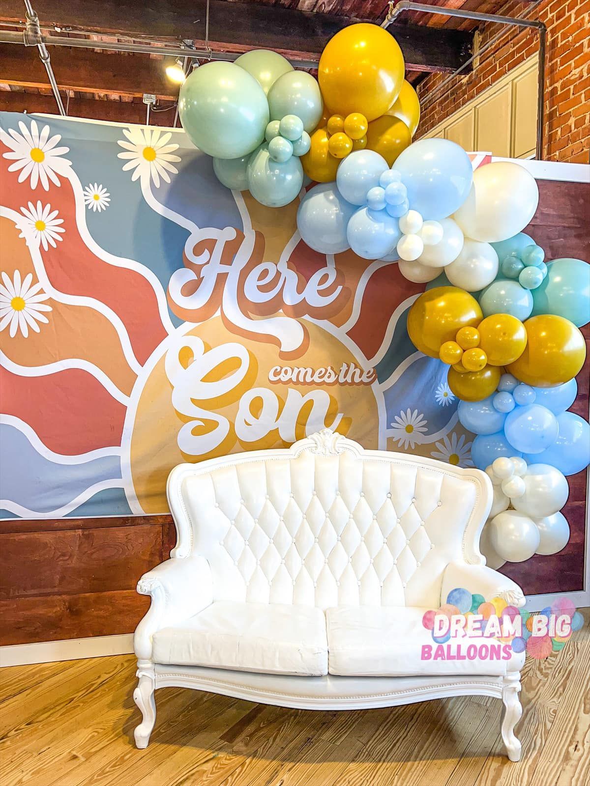 a white couch is sitting in front of a wall decorated with balloons