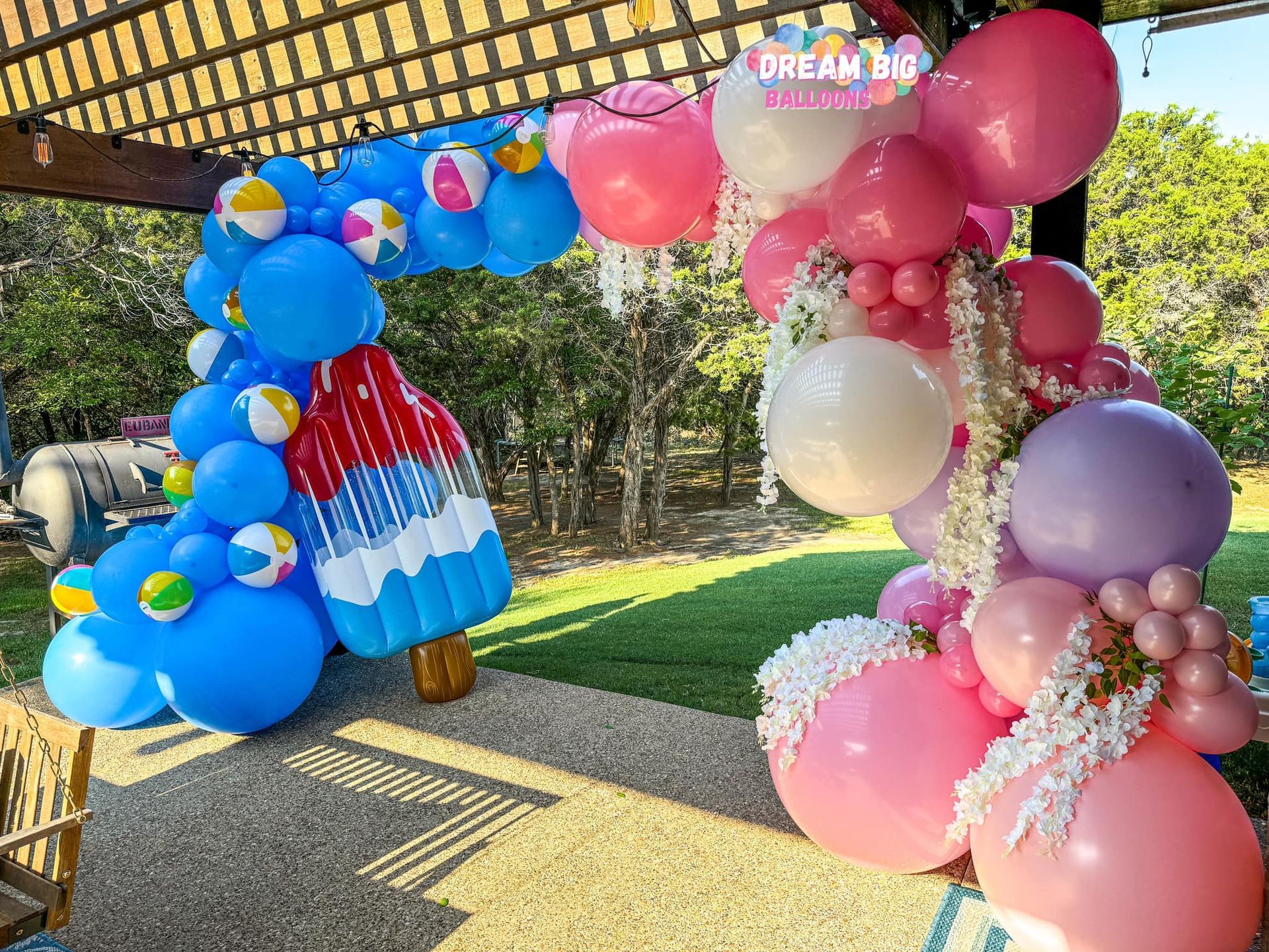 A bunch of balloons are sitting on the ground in a park.