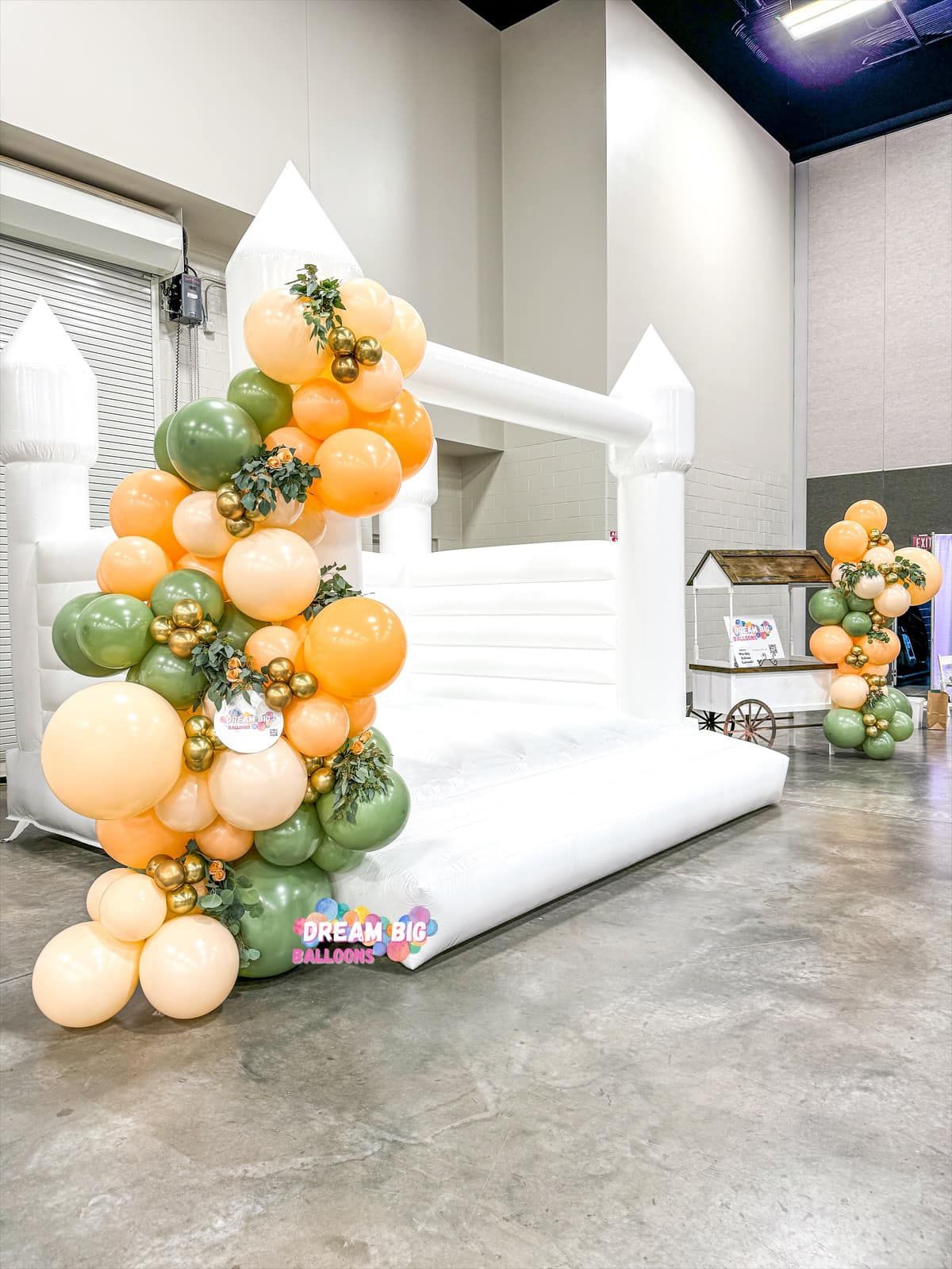 a white bouncy castle surrounded by balloons in a room