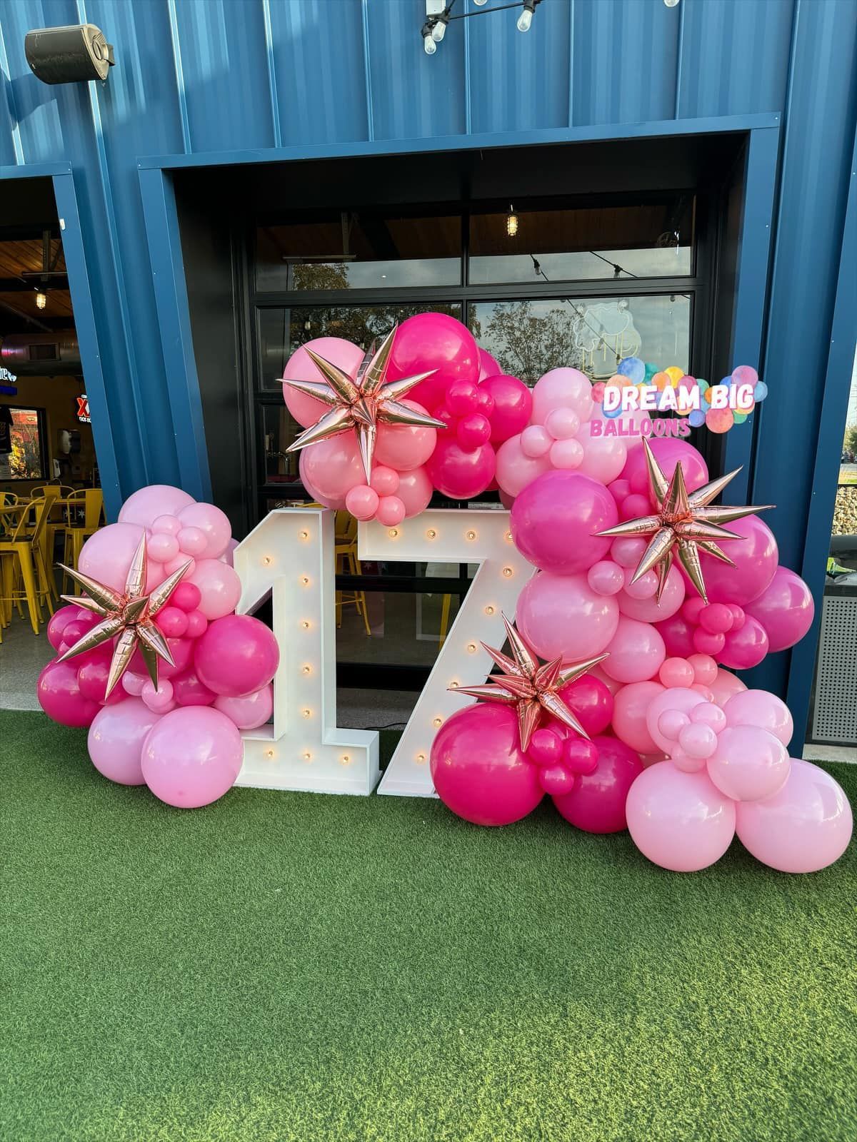A bunch of pink balloons are sitting in front of a building.