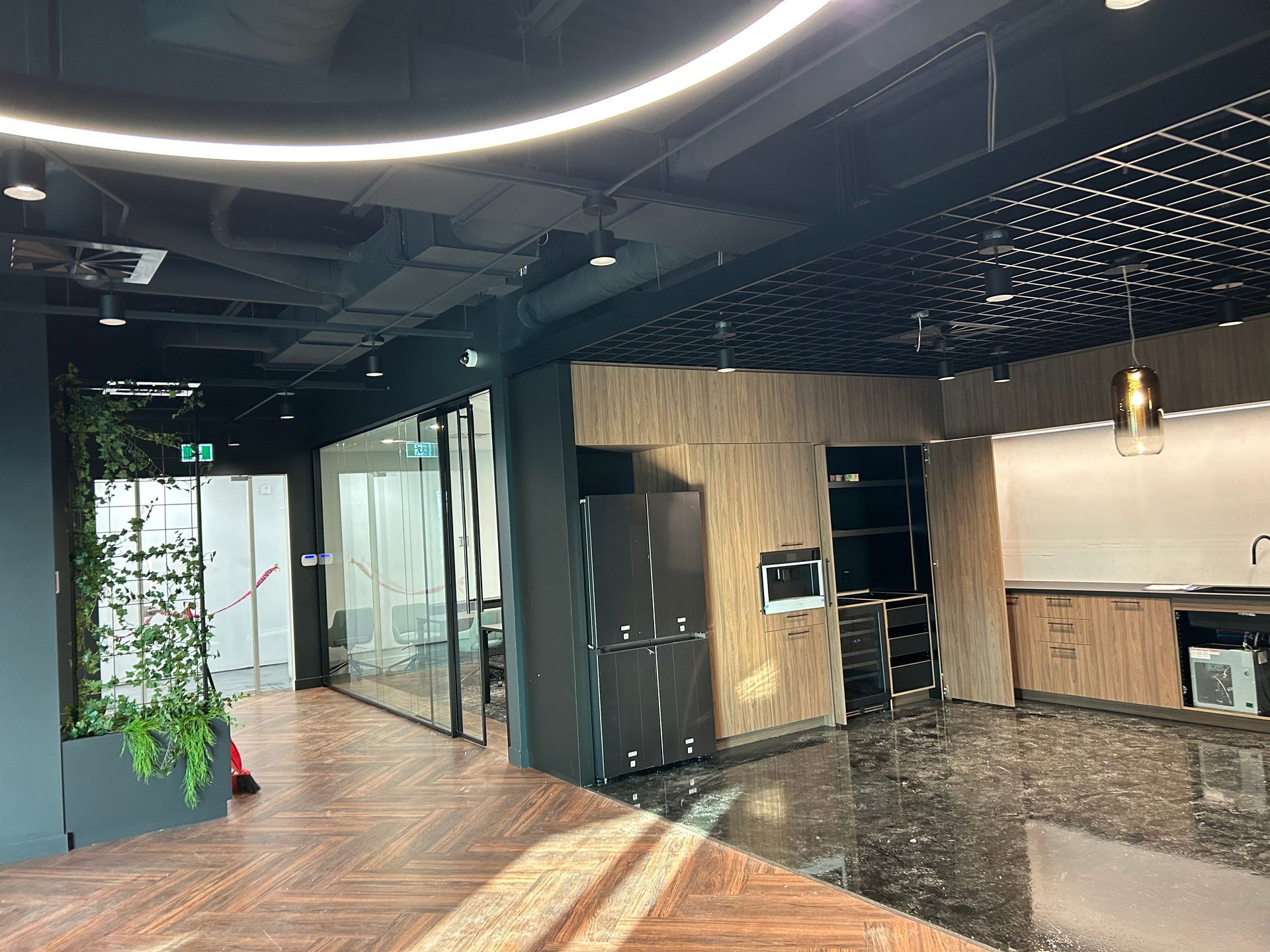 Espace de bureaux intérieur avec des touches de noir, des boiseries et une kitchenette.
