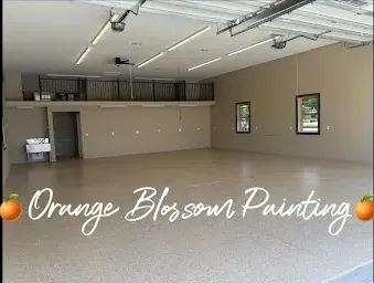 A large empty garage with the words `` orange blossom painting '' written on the floor.