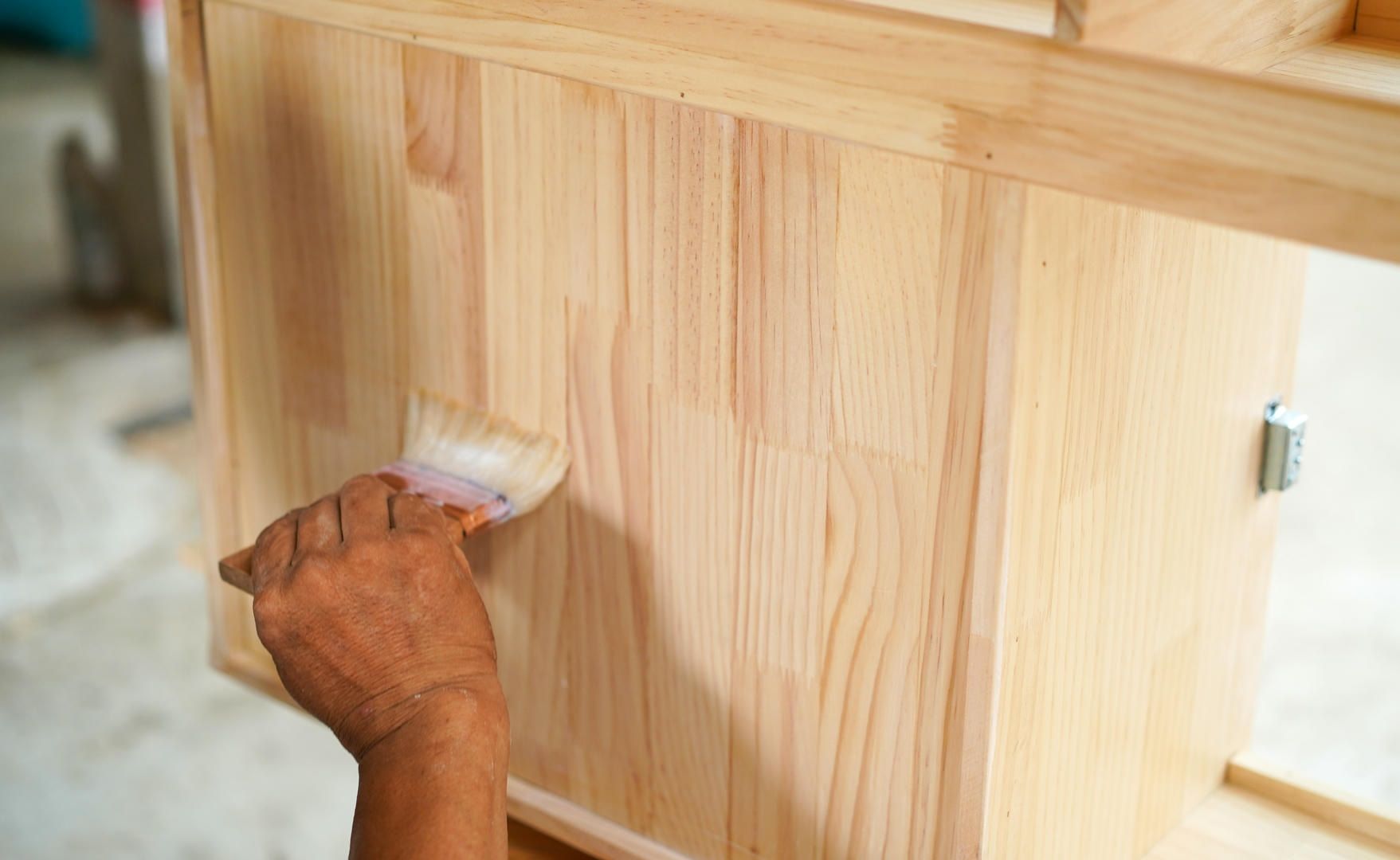 A person is painting a piece of wood with a brush.