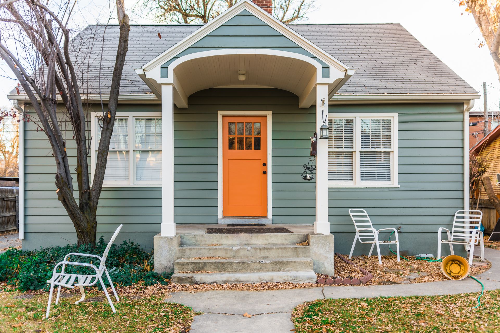 A small house with an orange door and a porch.