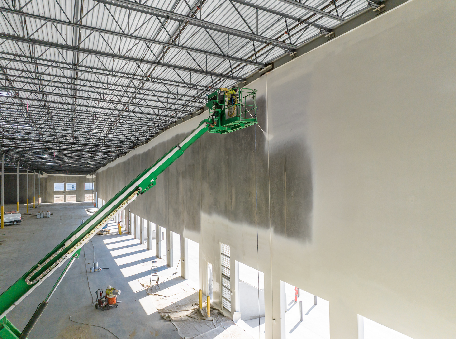 A man is painting a wall in a large warehouse.