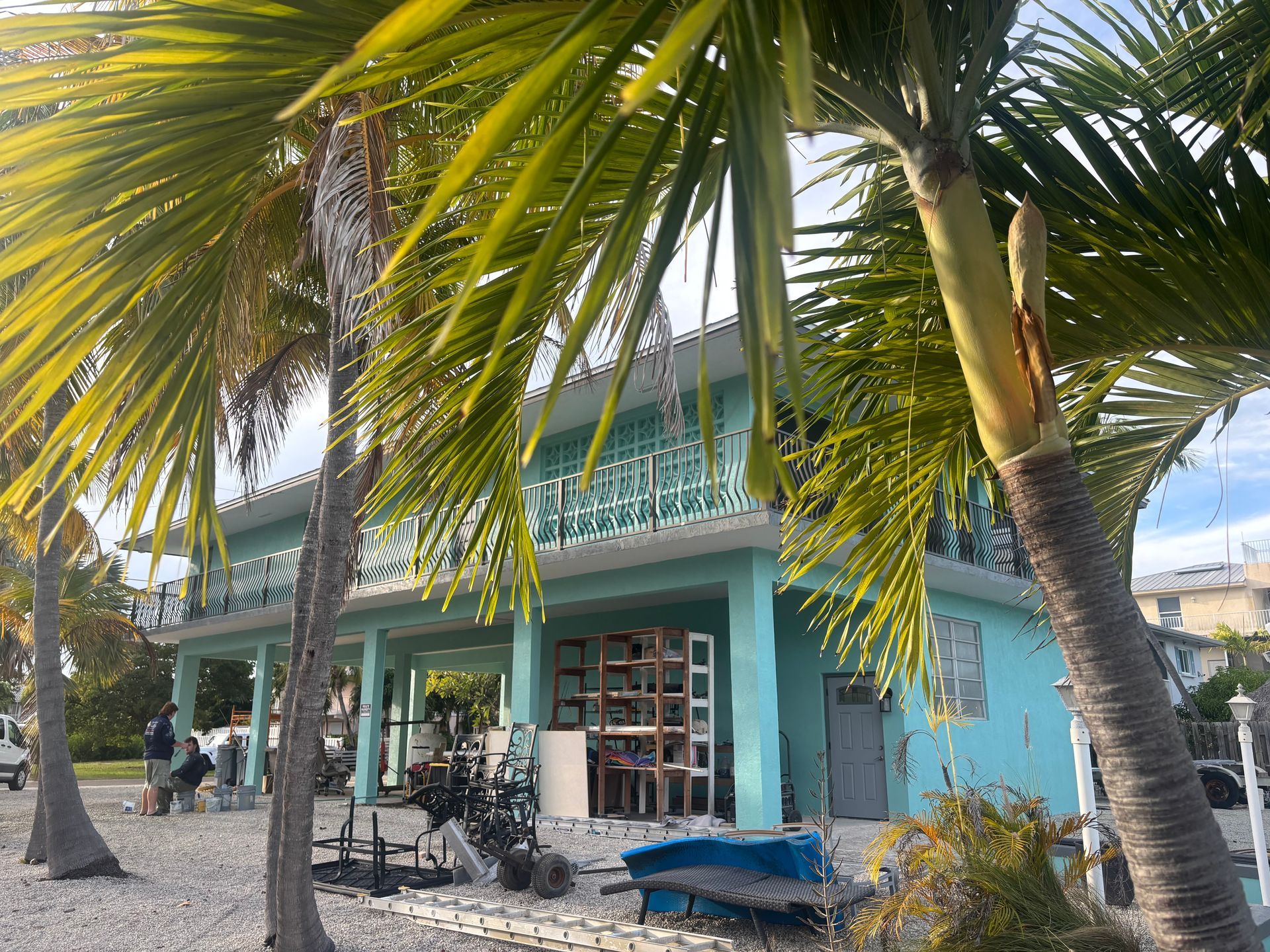 Turquoise beachside building with palm trees, bicycles, and lounge chairs in front