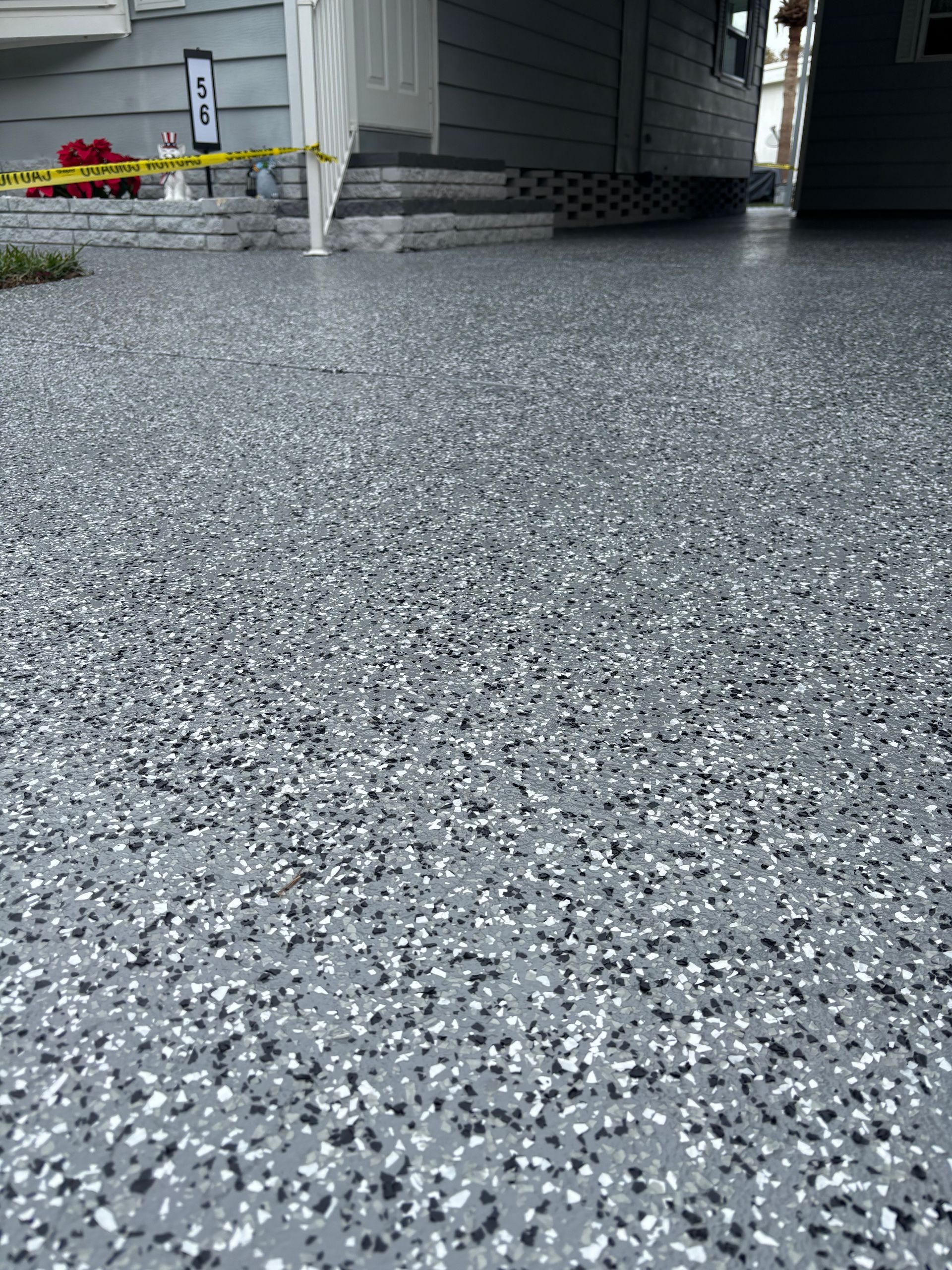 Close-up of speckled gray epoxy floor beside a house entrance with steps and siding