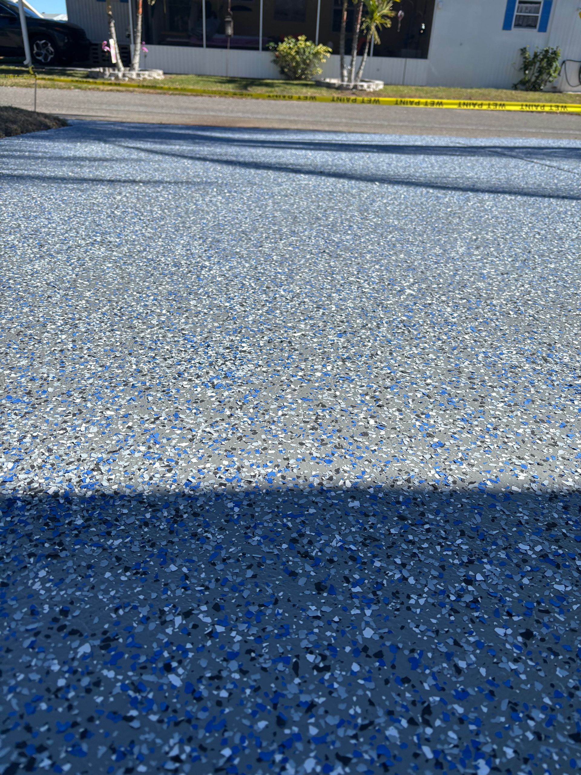 Blue-speckled pavement with a yellow curb and building in the background