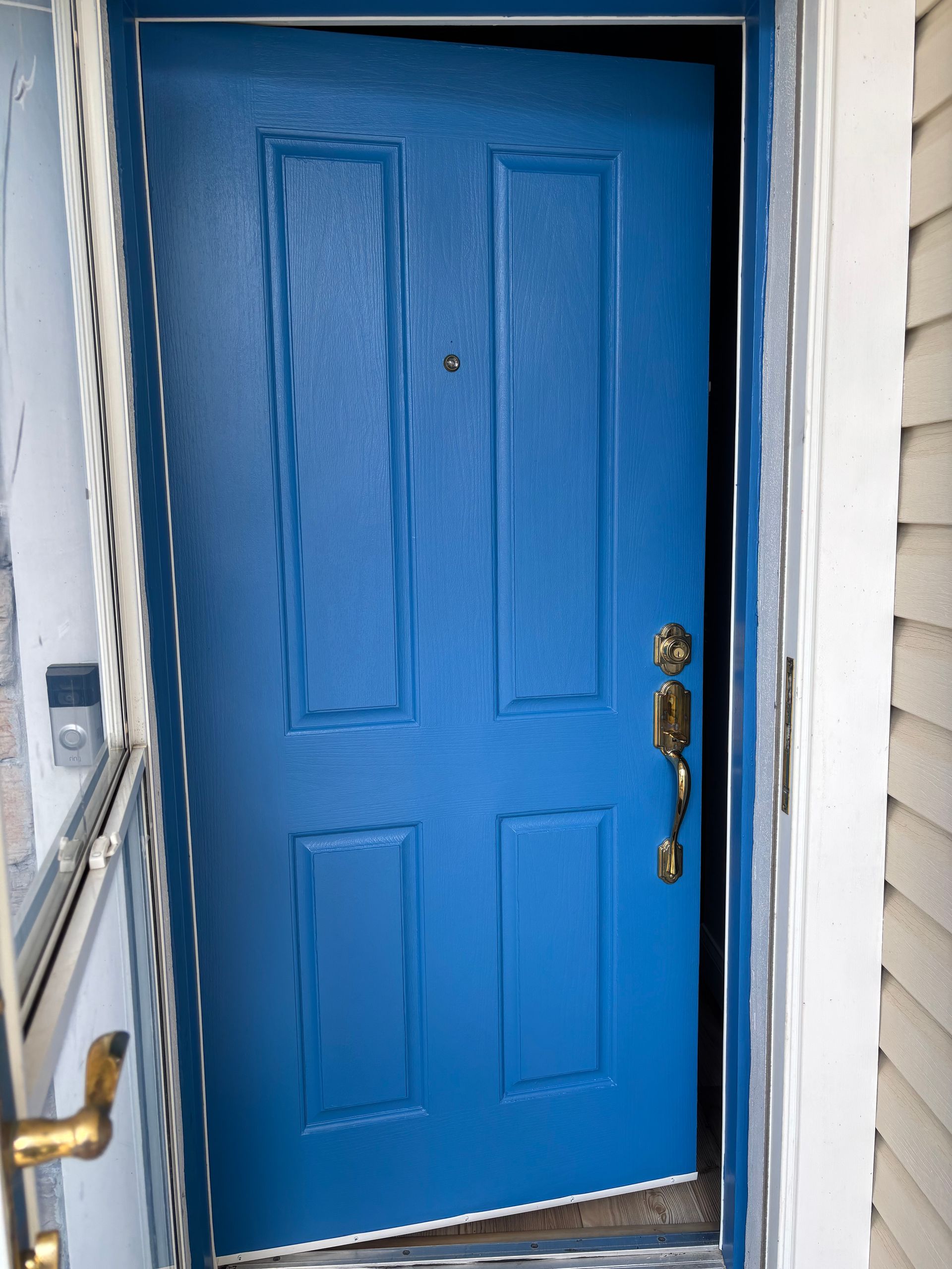 Bright blue front door with brass handle in a white doorway.