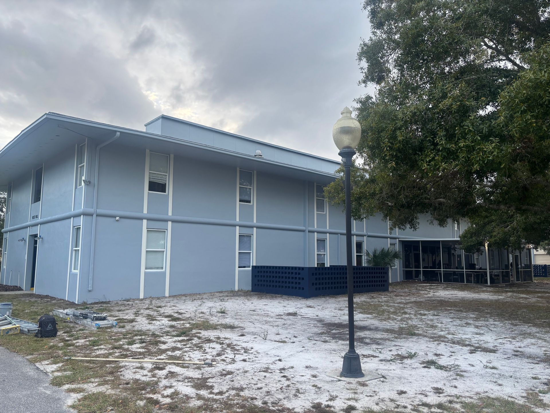 Two-story blue building with white trim, overcast sky, lamp post in foreground.