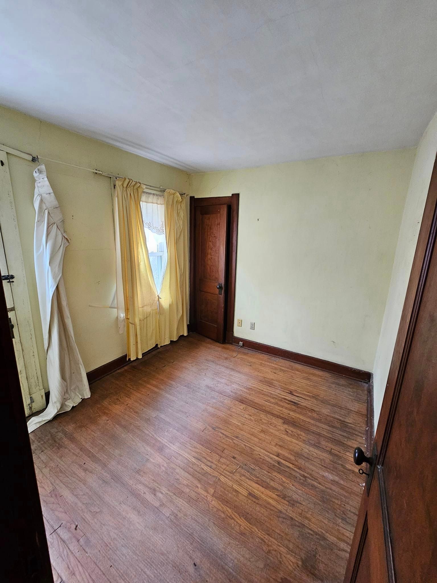 An empty room with hardwood floors and yellow walls.