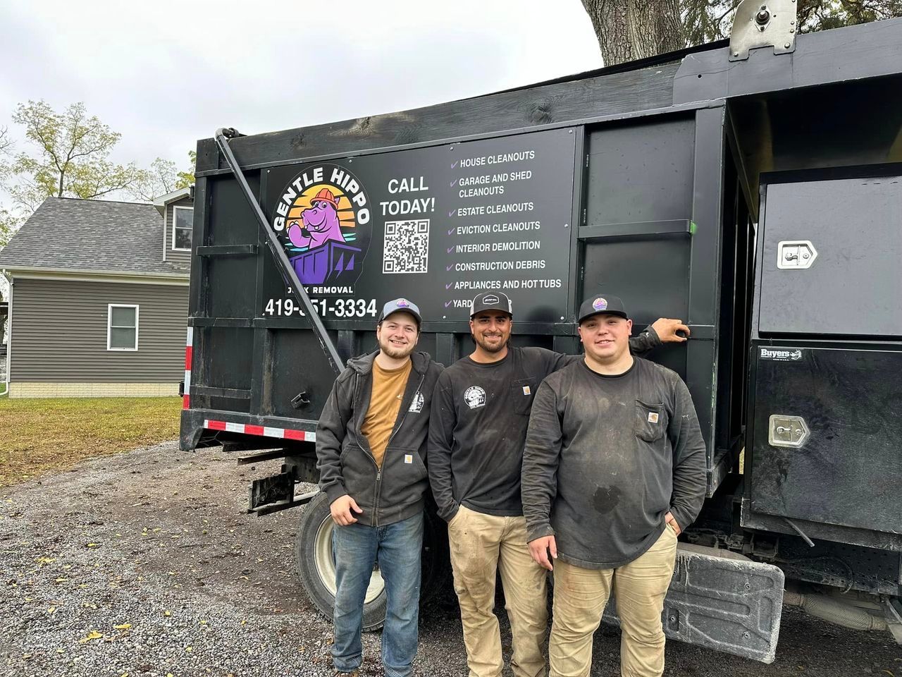 Three men are standing in front of a dump truck.
