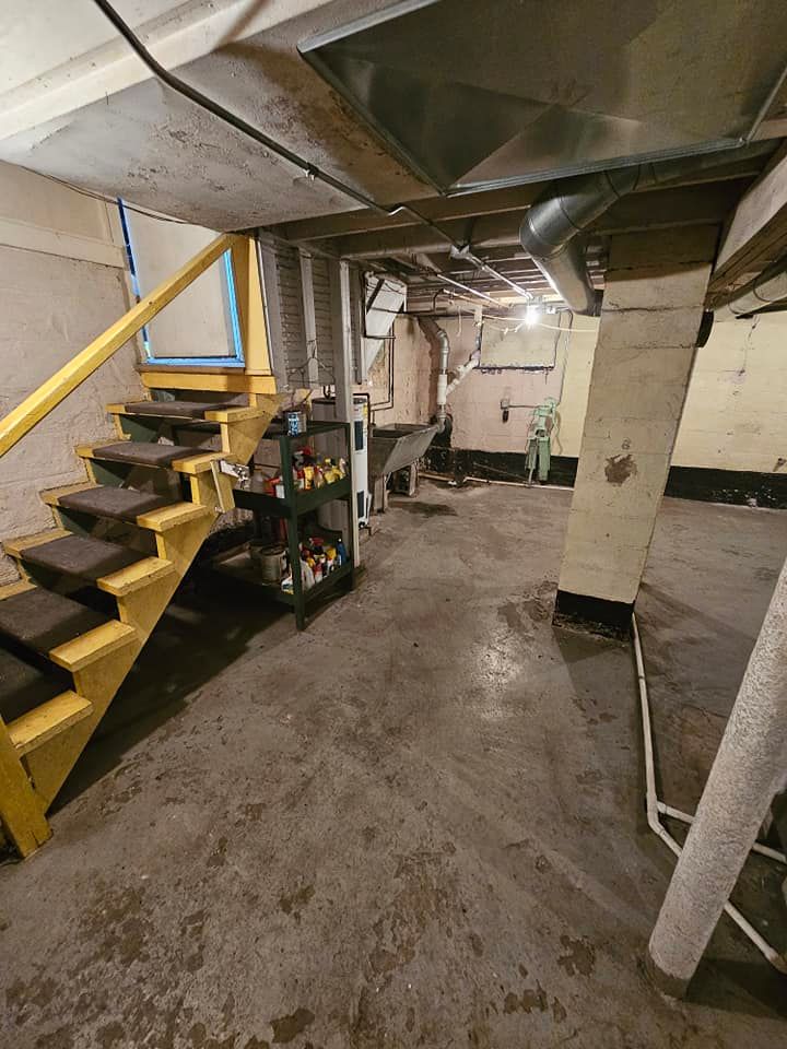 A basement with stairs and a shelf in it.