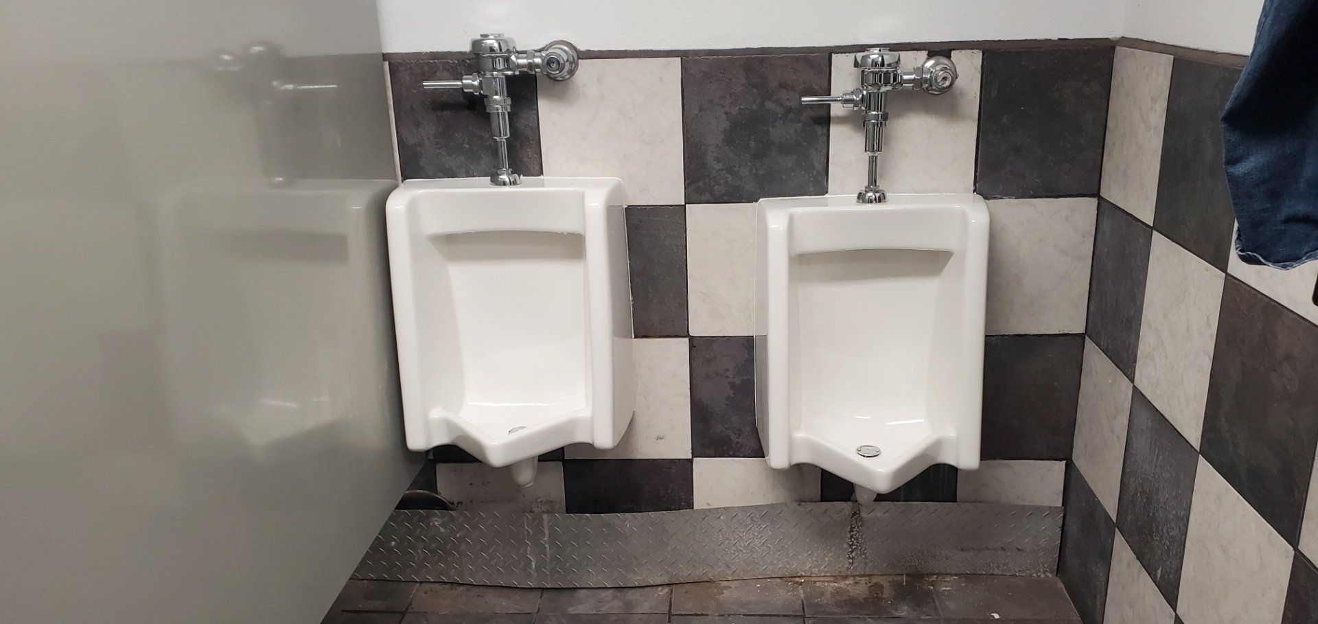 Two urinals are sitting next to each other in a bathroom.